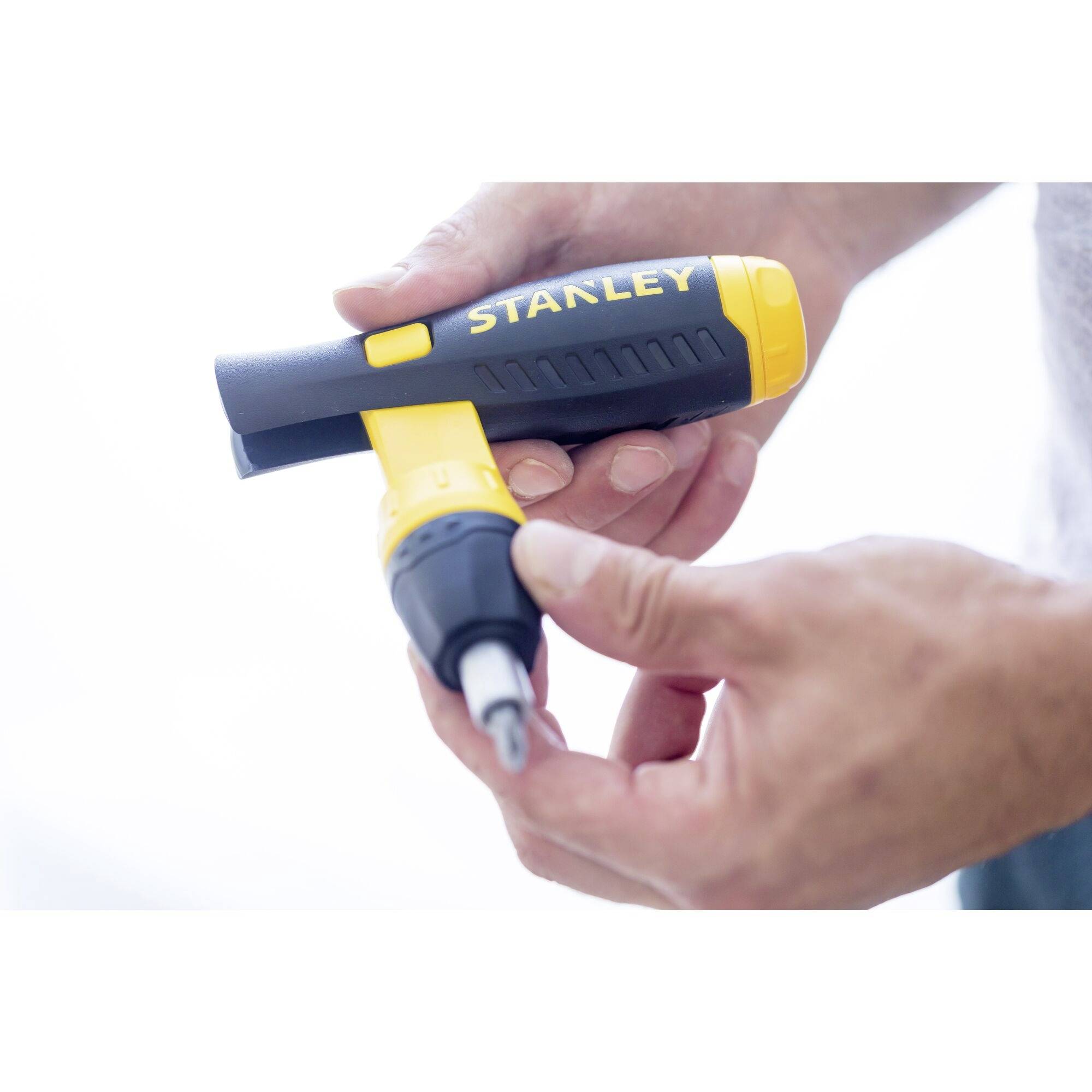 Osoba trzyma żółto-czarny elektryczny wkrętak marki Stanley, gotowy do użycia.