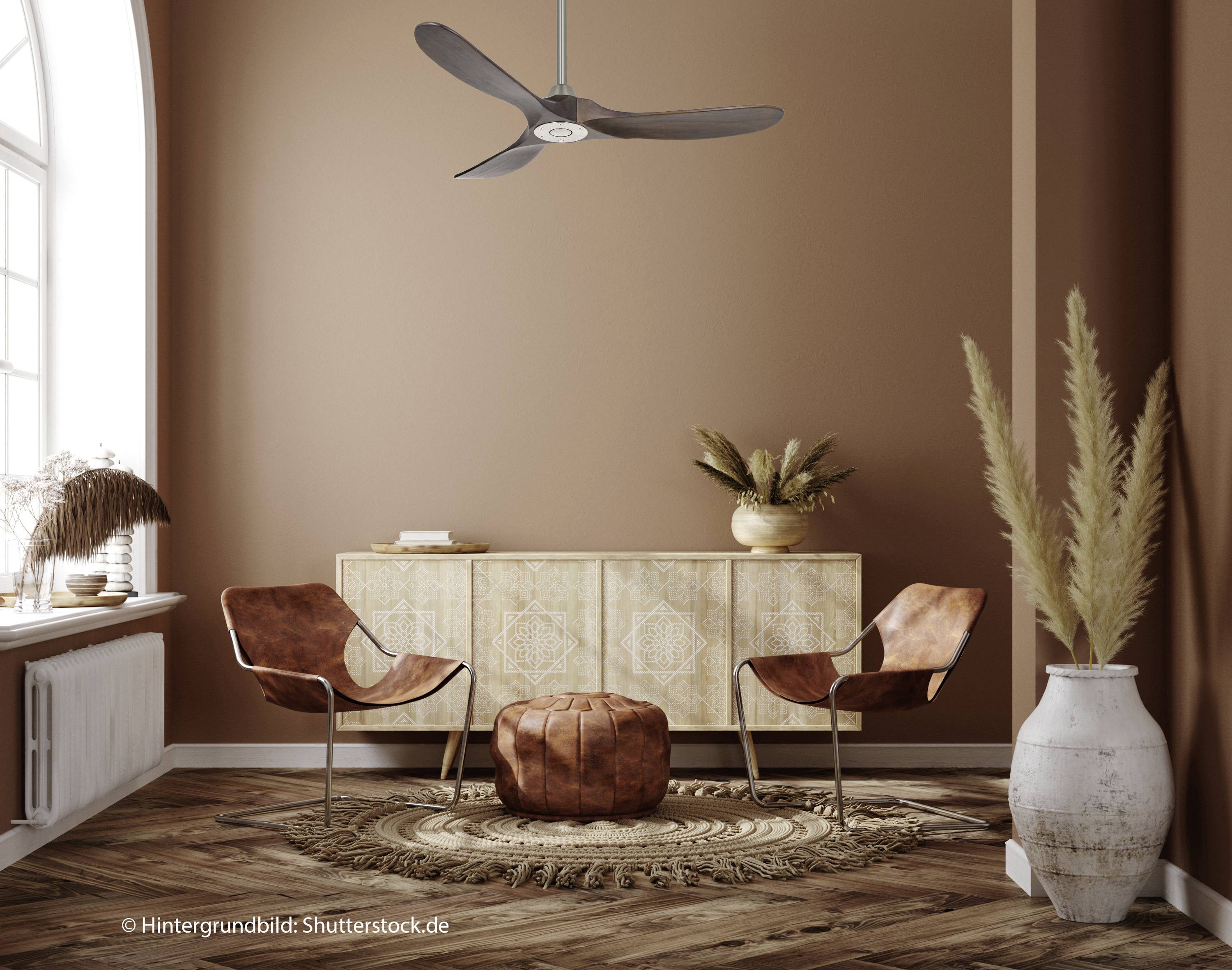 Stylowy pokój z dwoma brązowymi krzesłami, okrągłym podnóżkiem, dekoracyjnym dywanem i drewnianym stolikiem. Ściana w ciepłym odcieniu brązu.