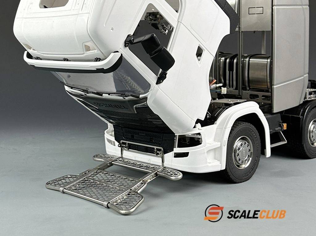 Model ciężarówki z podniesionym dachem kabiny, widocznym silnikiem. Rozłożony srebrny stopień, logo 'ScaleClub' w prawym dolnym rogu.