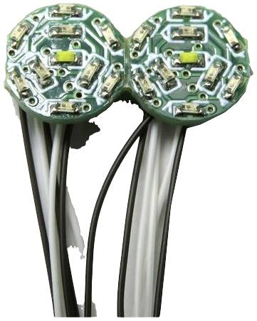 Zbliżenie dwóch połączonych, okrągłych, zielonych obwodów drukowanych z widocznymi elementami elektronicznymi i przewodami.