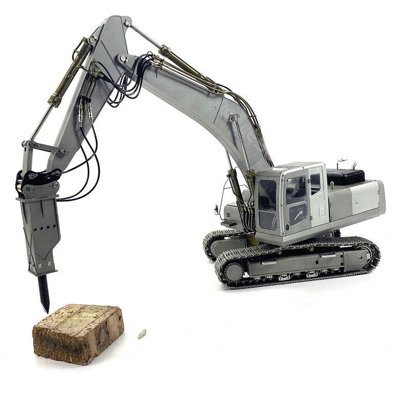 Szary koparka gąsienicowy z młotem wyburzeniowym rozbija duży blok skalny.