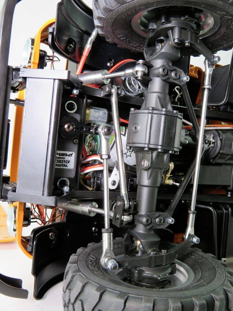 Zbliżenie zdalnie sterowanego samochodu modelarskiego; ukazuje oś, zawieszenie i okablowanie. Techniczny wgląd w budowę pojazdu.