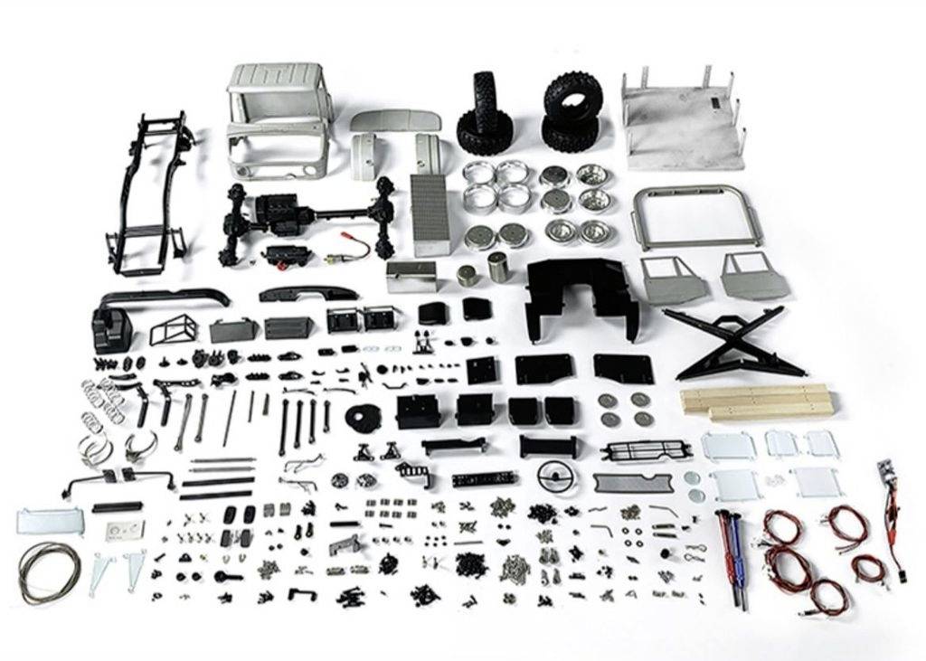 Zestaw do składania modelu samochodu na białym tle. Liczne części samochodowe i elementy wyposażenia są rozłożone w uporządkowany sposób.