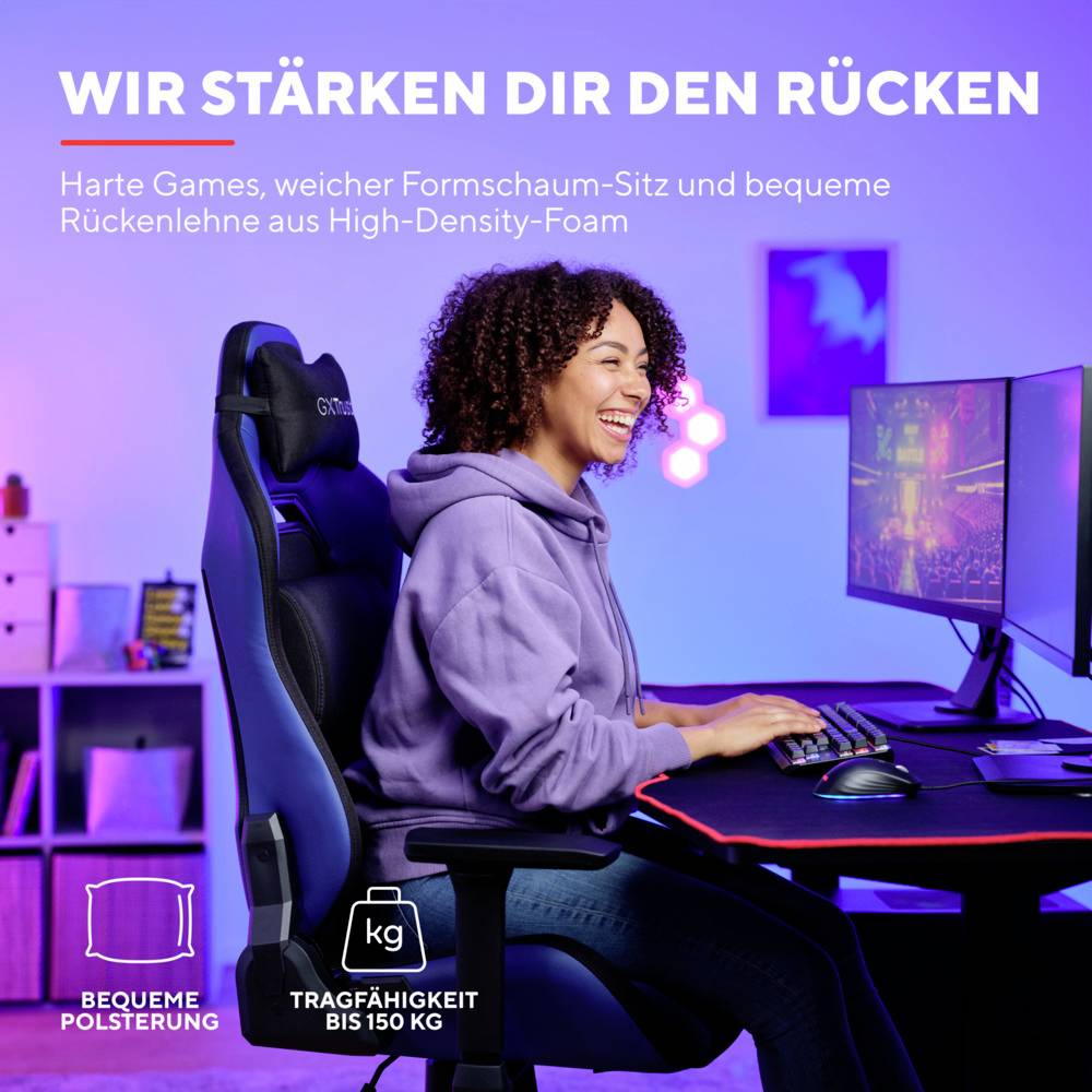 Kobieta siedzi swobodnie na fotelu gamingowym przed komputerem; tekst: 'Wspieramy twój kręgosłup'. Podkreśla komfort i wsparcie krzesła.
