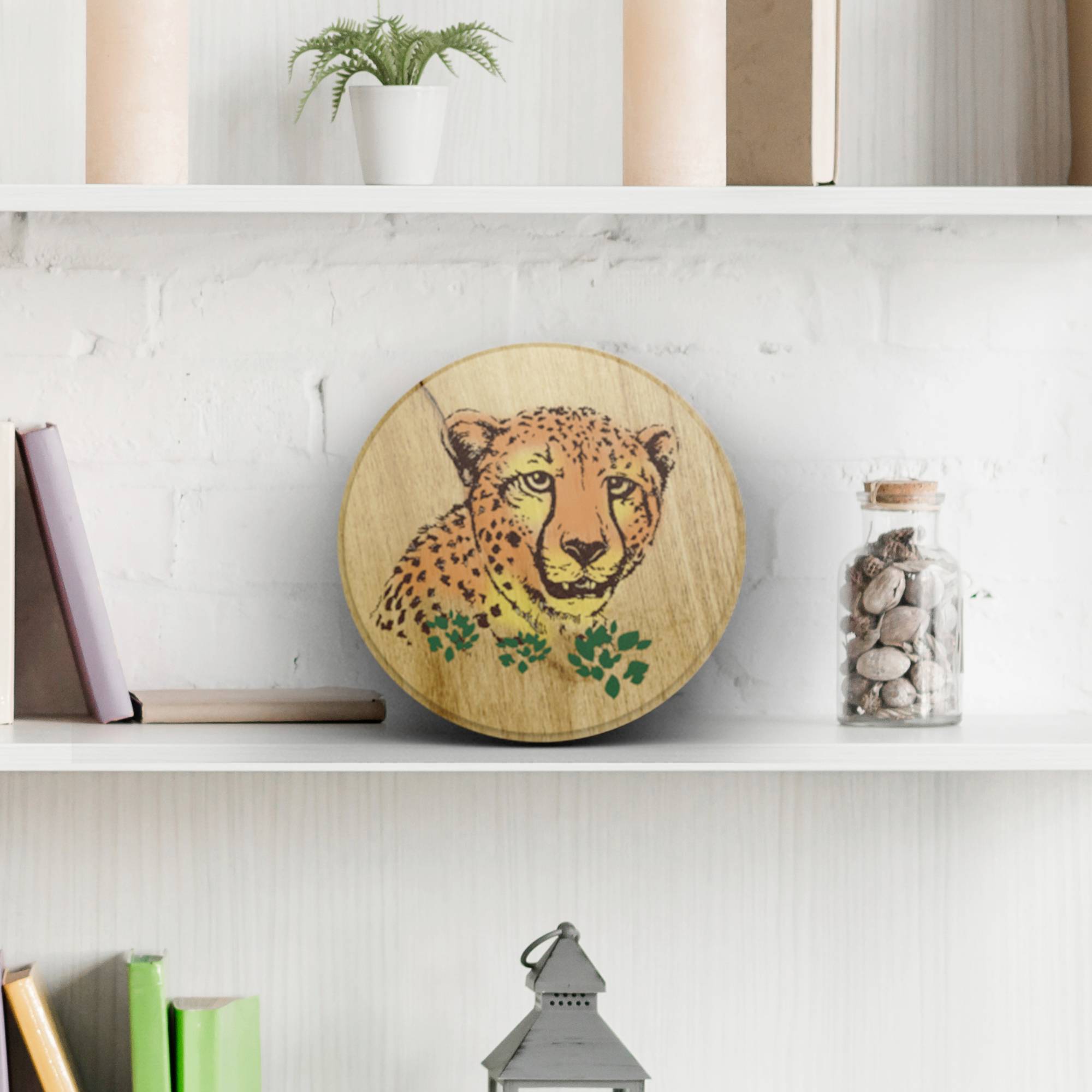 Okrągła drewniana deska z motywem lamparta, umieszczona na regale. Wokół znajdują się dekoracyjne książki i rośliny.