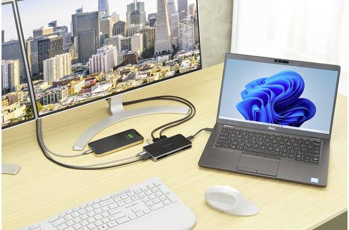 Nowoczesne stanowisko pracy z dwoma monitorami, laptopem z ekranem Windows, klawiaturą i myszą na drewnianym biurku.