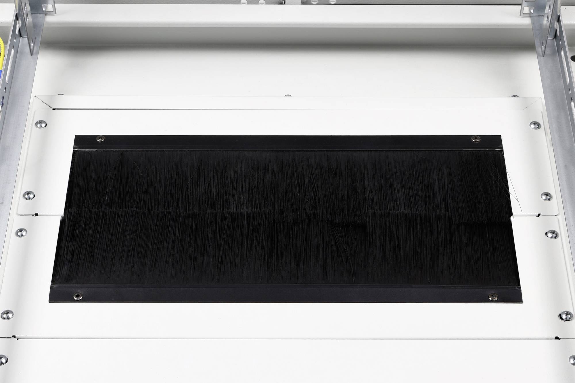 Przemysłowa maszyna z prostokątną szczotką pośrodku, używana do czyszczenia lub przetwarzania materiałów.