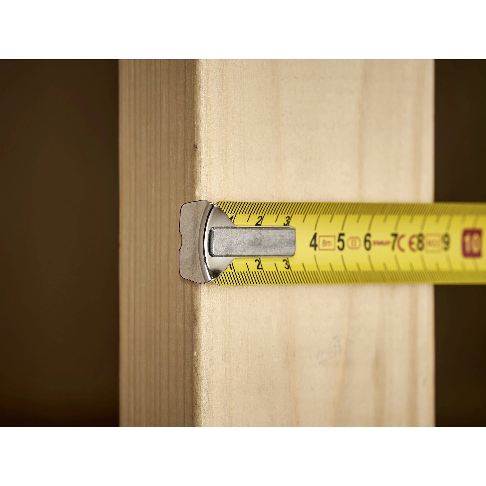 Miarka mierzy szerokość belki drewnianej. Oznaczenie wskazuje 3,5 cm.