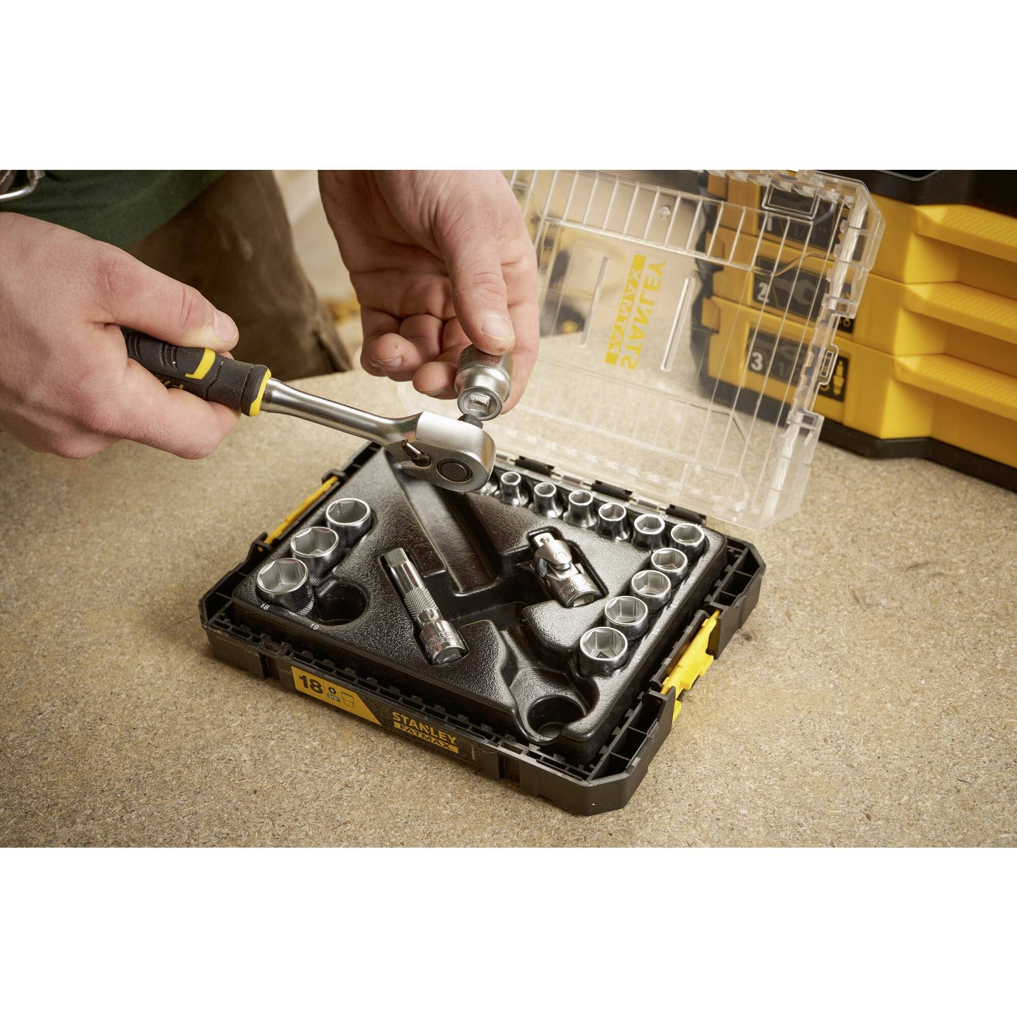 Osoba pracuje z zestawem kluczy nasadowych. Różne nasadki widoczne w otwartej walizce. Główny nacisk na sposób użycia.