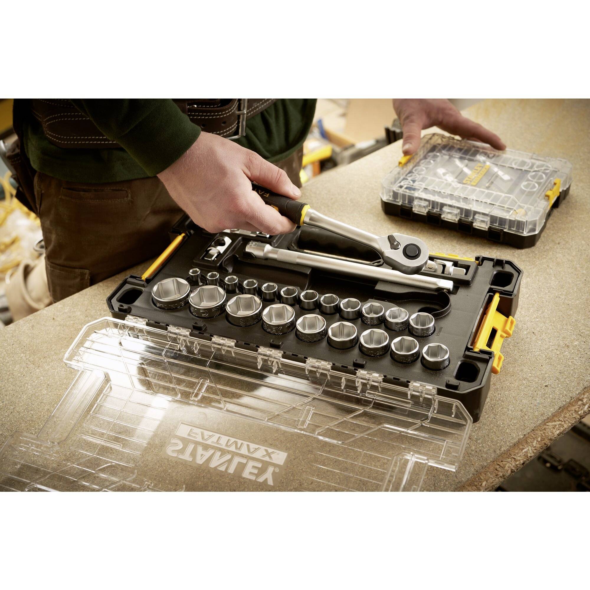 Osoba używa zestawu kluczy nasadowych. Różne nasadki i klucz dynamometryczny są widoczne w otwartym etui.