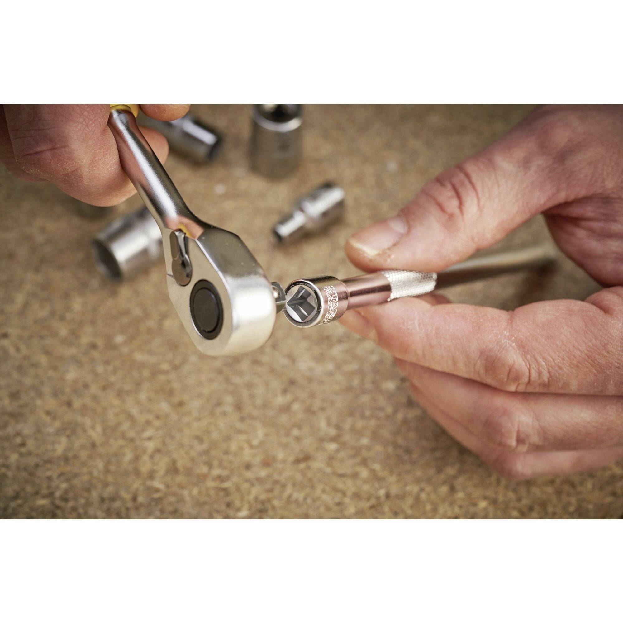 Jedna ręka trzyma grzechotkę, podczas gdy druga wkłada bit do grzechotki. W tle widać kilka bitów.