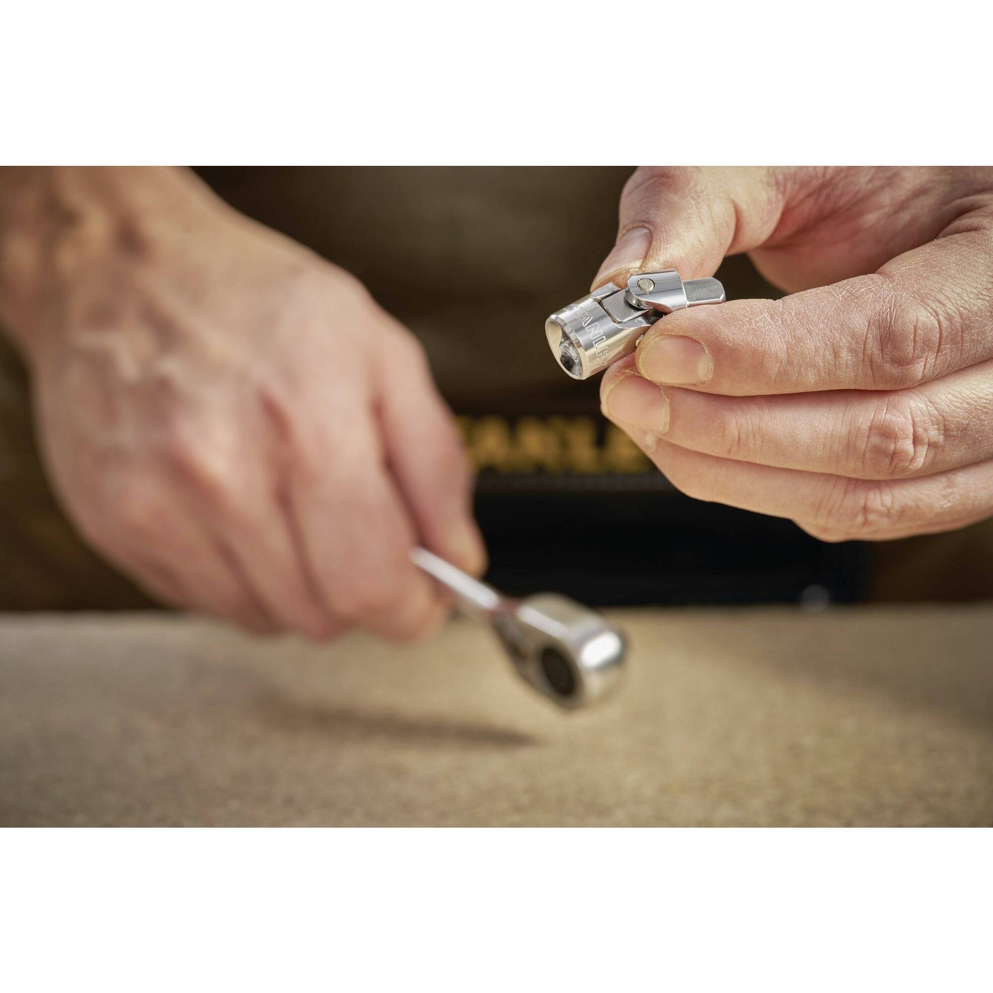 Osoba trzyma nakrętkę w prawej ręce i zestaw kluczy nasadowych w lewej, gotowa do montażu.