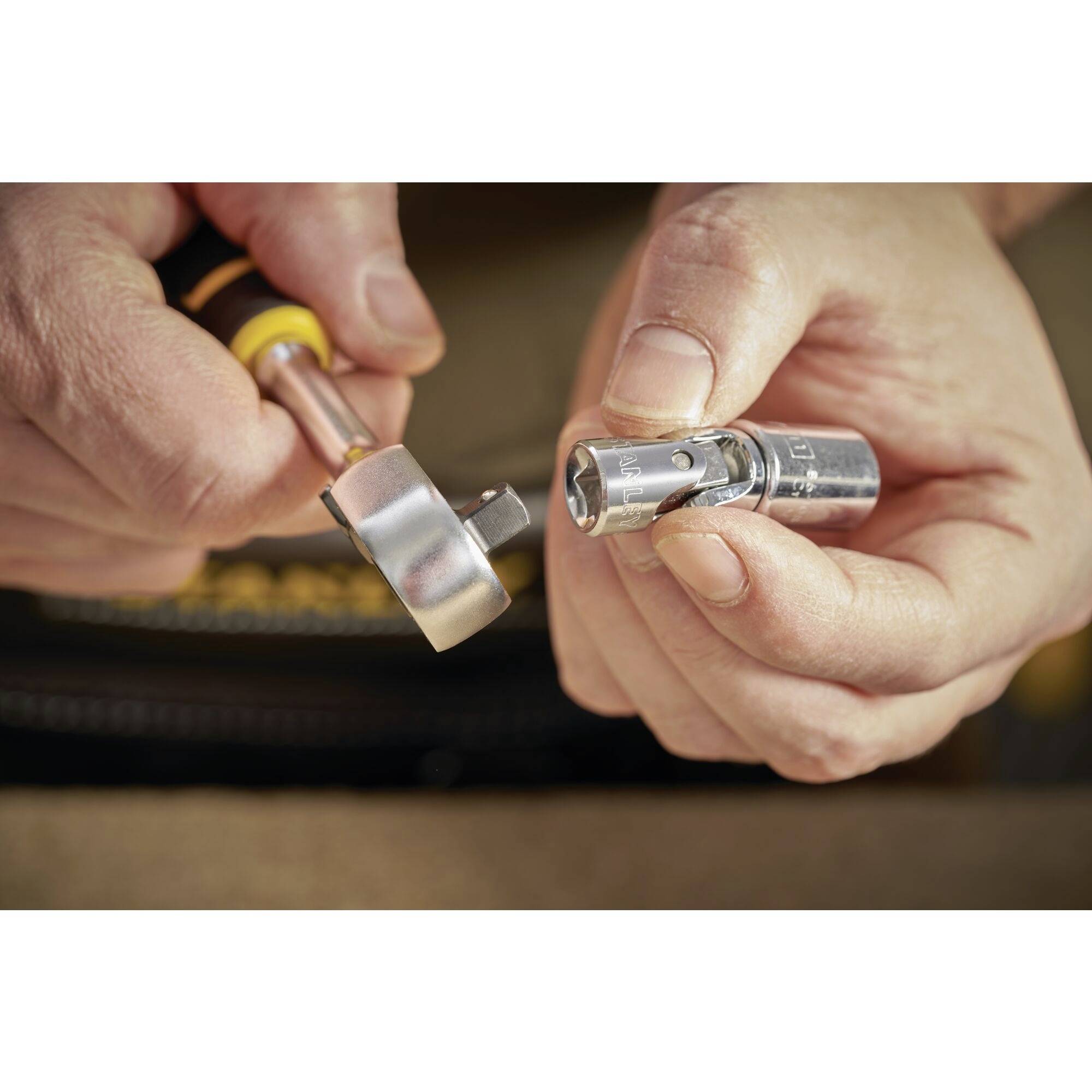 Dwie ręce trzymają zbliżenie narzędzi: klucz zapadkowy i nasadkę. Narzędzia są przygotowywane do montażu.