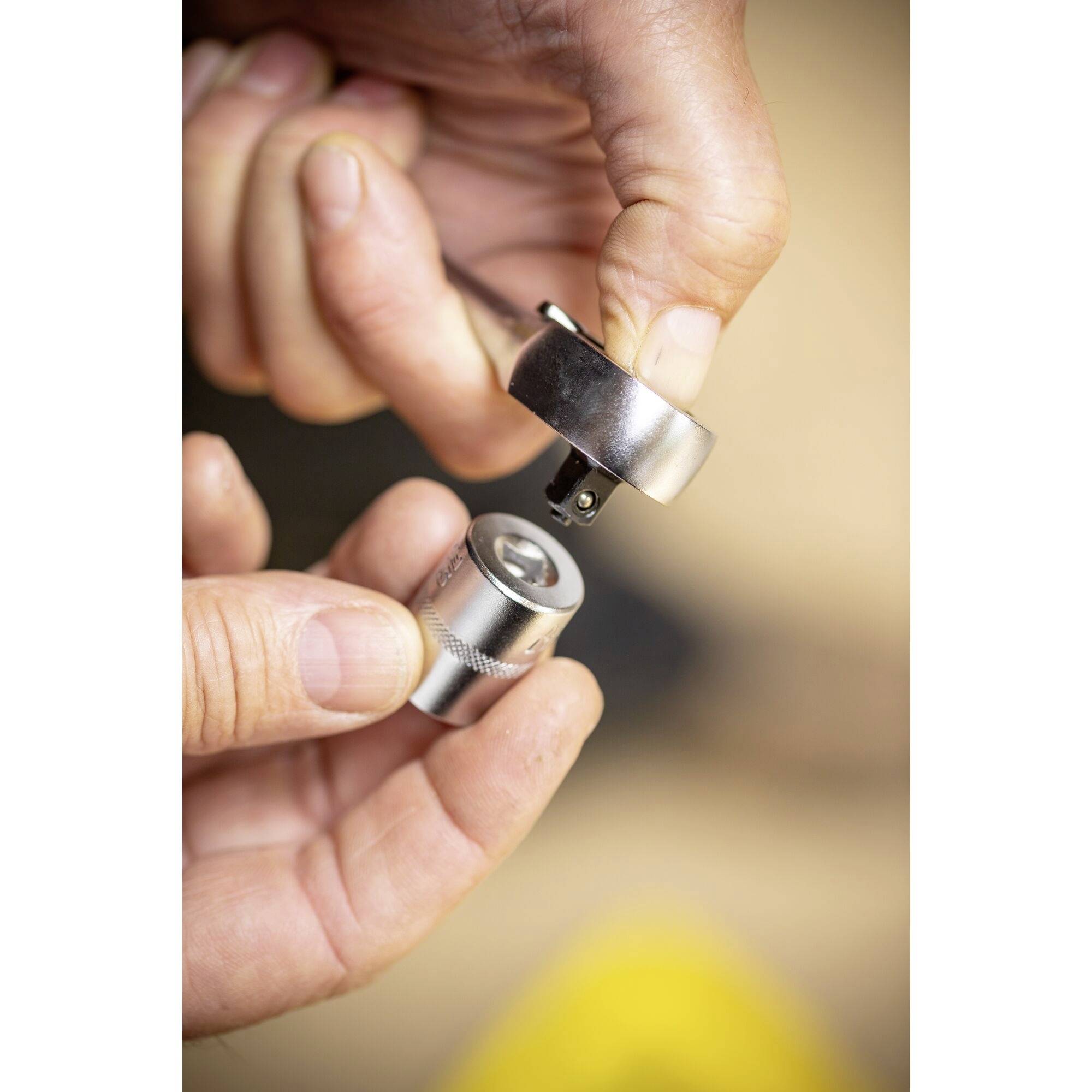 Dwie ręce trzymają chromowany zestaw adapterów kluczy nasadowych. Jeden element jest umieszczony powyżej drugiego, aby je połączyć.