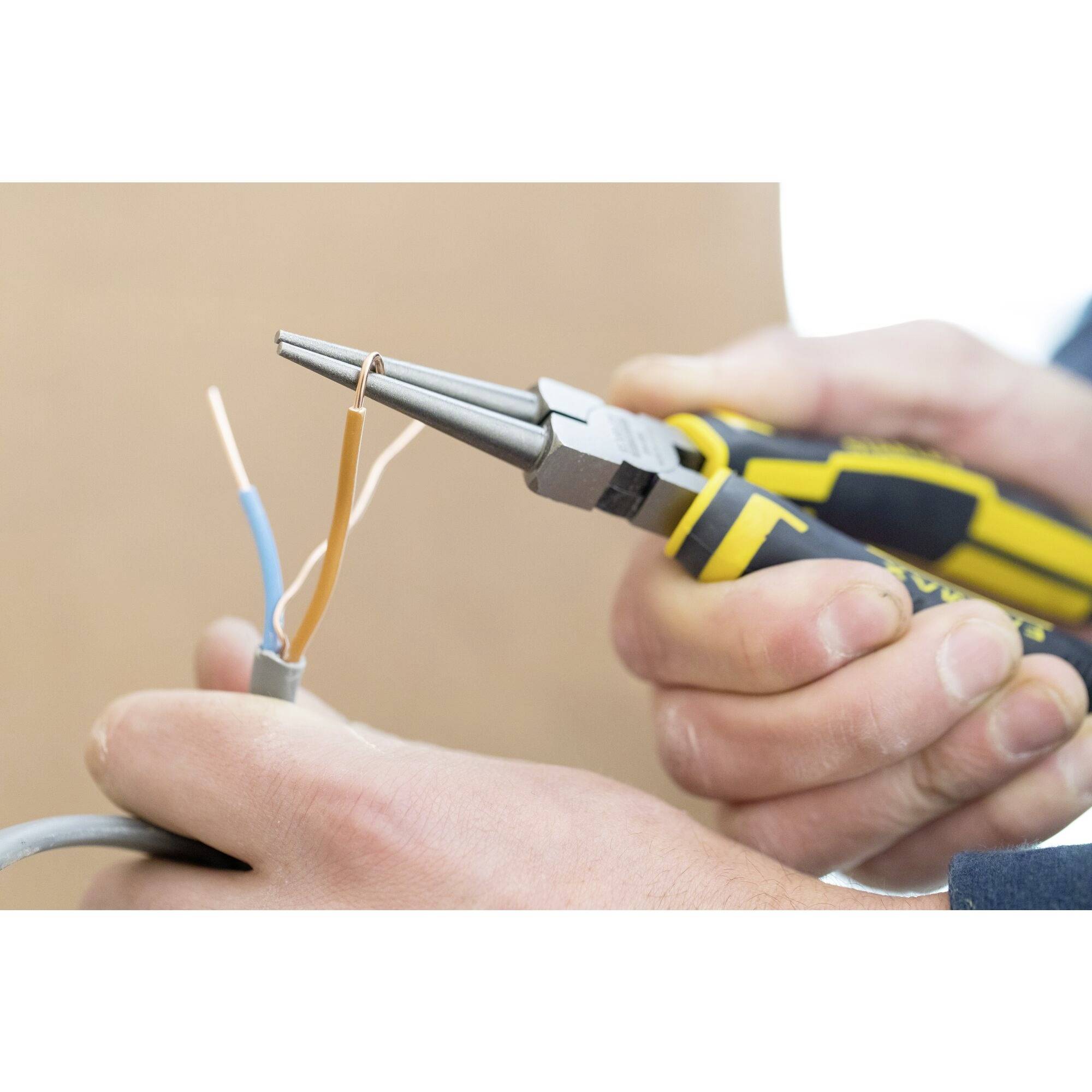 Osoba trzyma obcinacz i usuwa izolację plastikową z przewodów, odsłaniając wewnętrzne przewody miedziane.