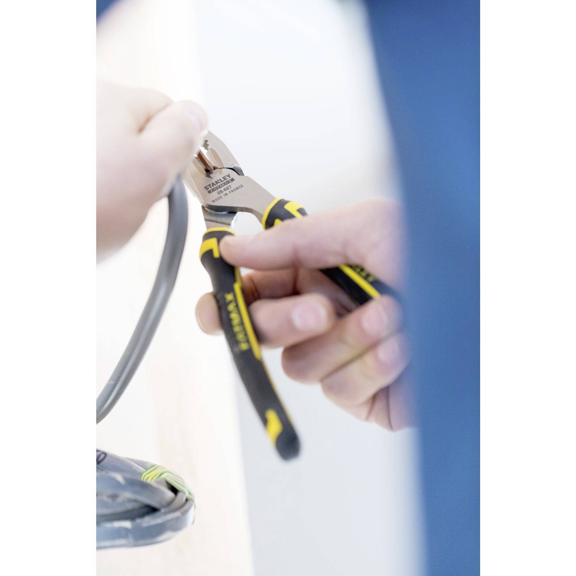 Dwie ręce trzymają szczypce do cięcia drutu i przecinają kabel.