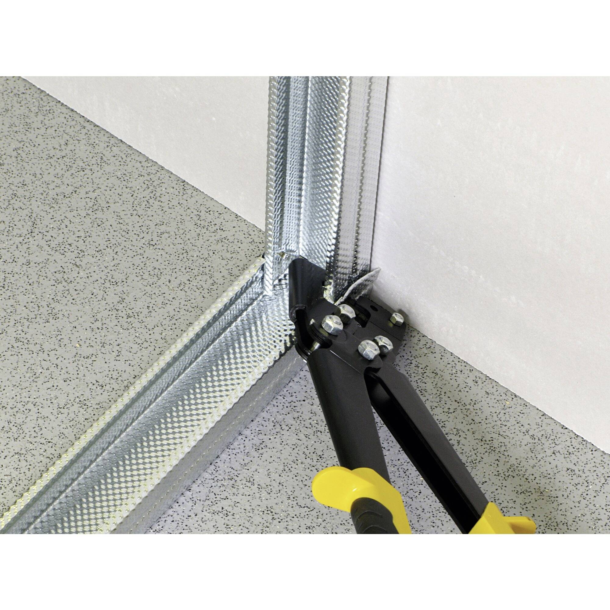 Narzędzie tnie profil metalowy w rogu. Ilustruje zastosowanie nożyc do blachy podczas skracania elementów łączących w ramie ściennej.