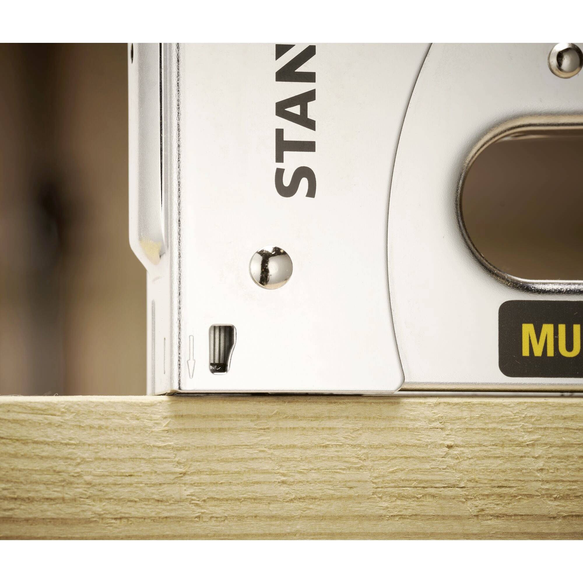 Na drewnianym stole leży chromowany suwmiarz. Widoczna jest tylko część skali i pokrętło regulacyjne.