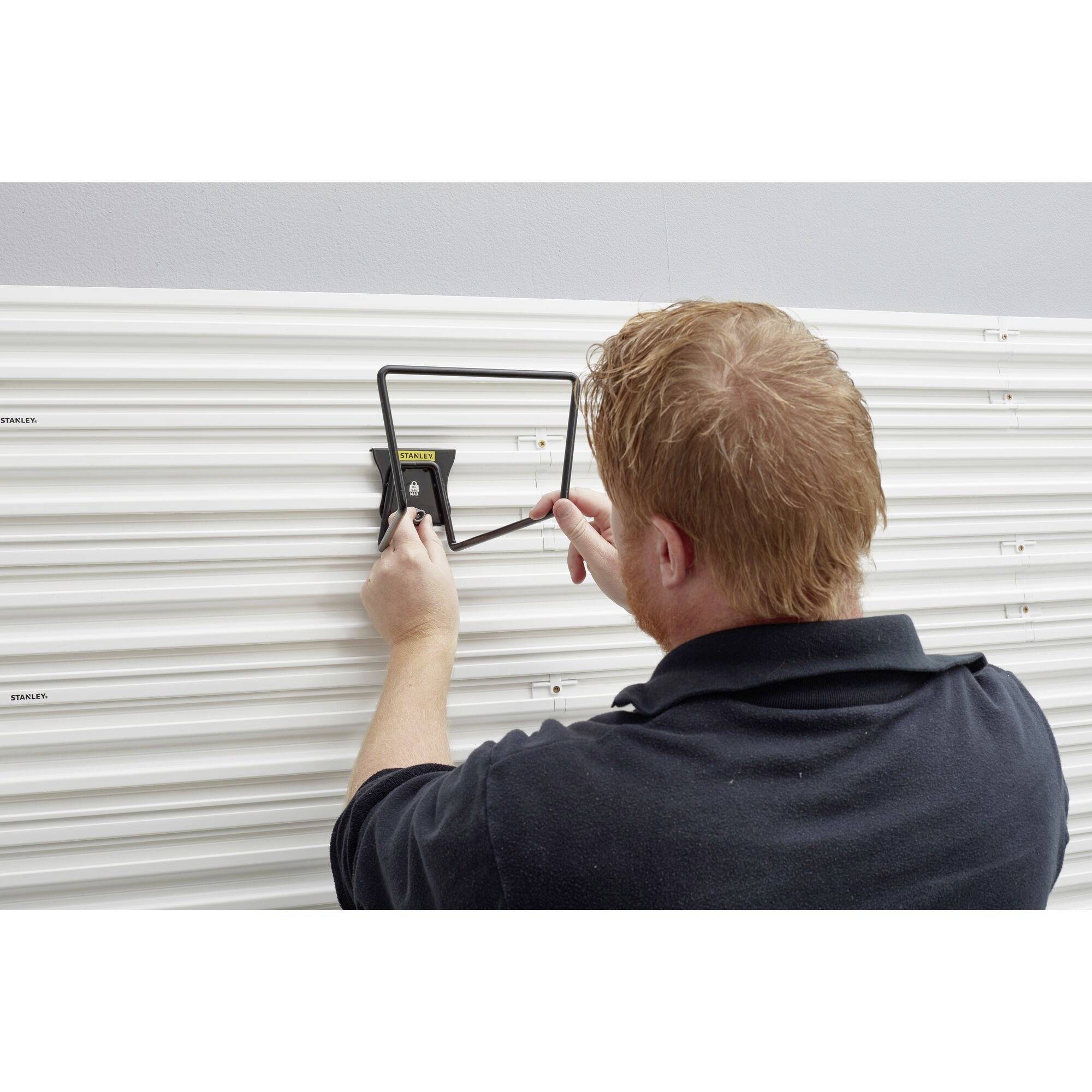 Osoba naprawia lub montuje metalową roletę, używając narzędzia. Roleta ma poziomy styl lamelowy.