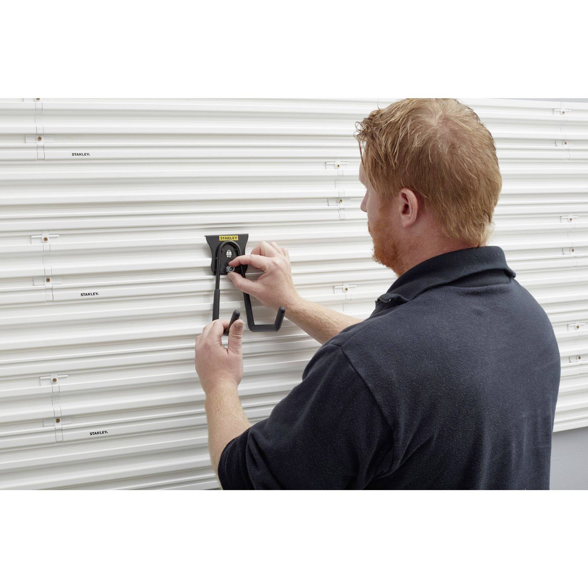 Osoba mierzy odległość między dwoma punktami na metalowej powierzchni bramy rolowanej za pomocą suwmiarki.