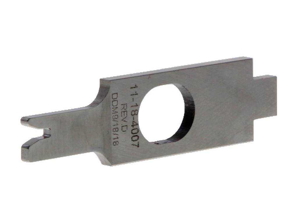 Metalowy element o prostokątnym kształcie, z dużym otworem pośrodku i małym otworem przy jednym z końców. Na powierzchni wygrawerowane są cyfry i litery.
