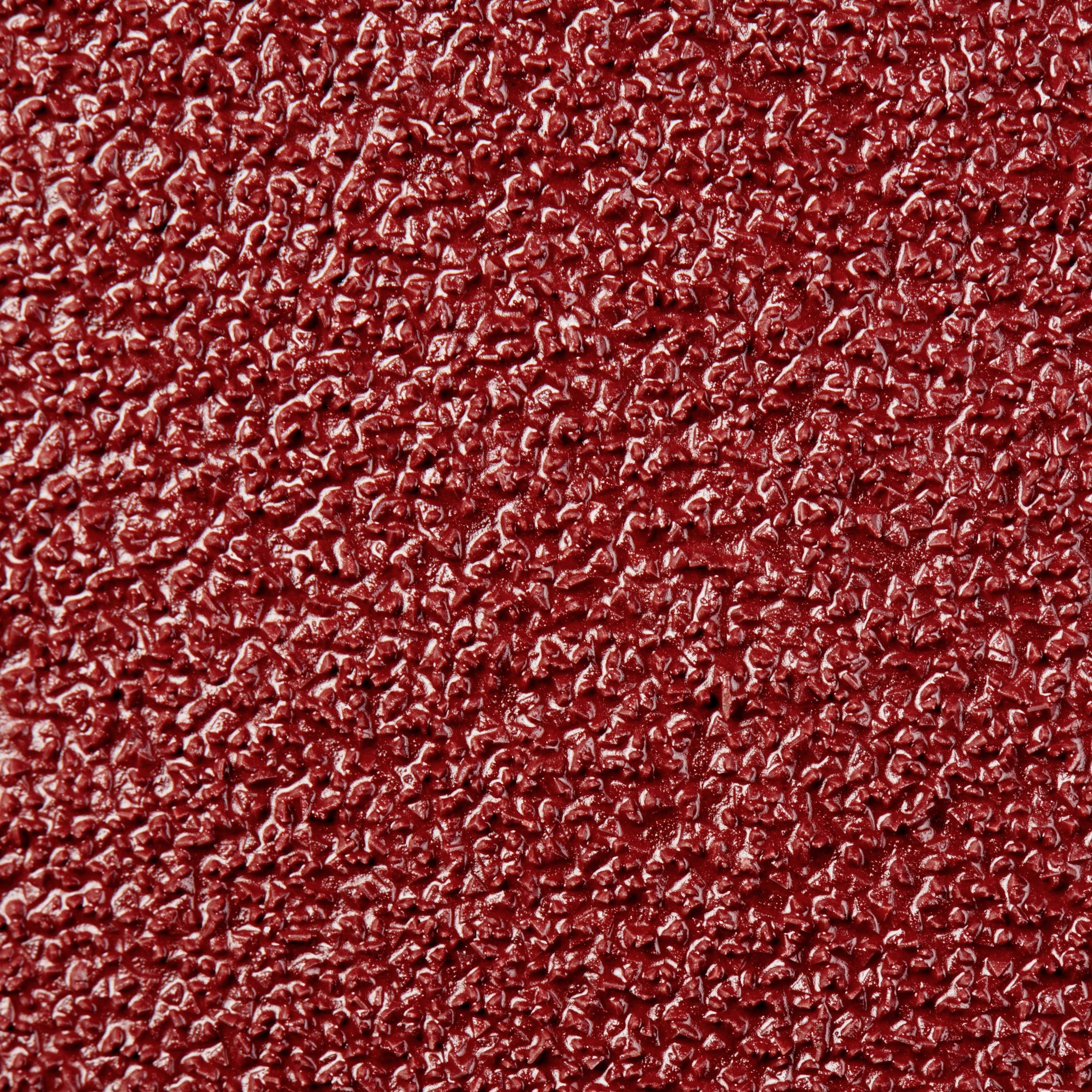 Szorstka, chropowata powierzchnia, przypominająca gruboziarnisty papier ścierny, wykazuje jednorodną teksturę z małymi wypukłościami i zagłębieniami.