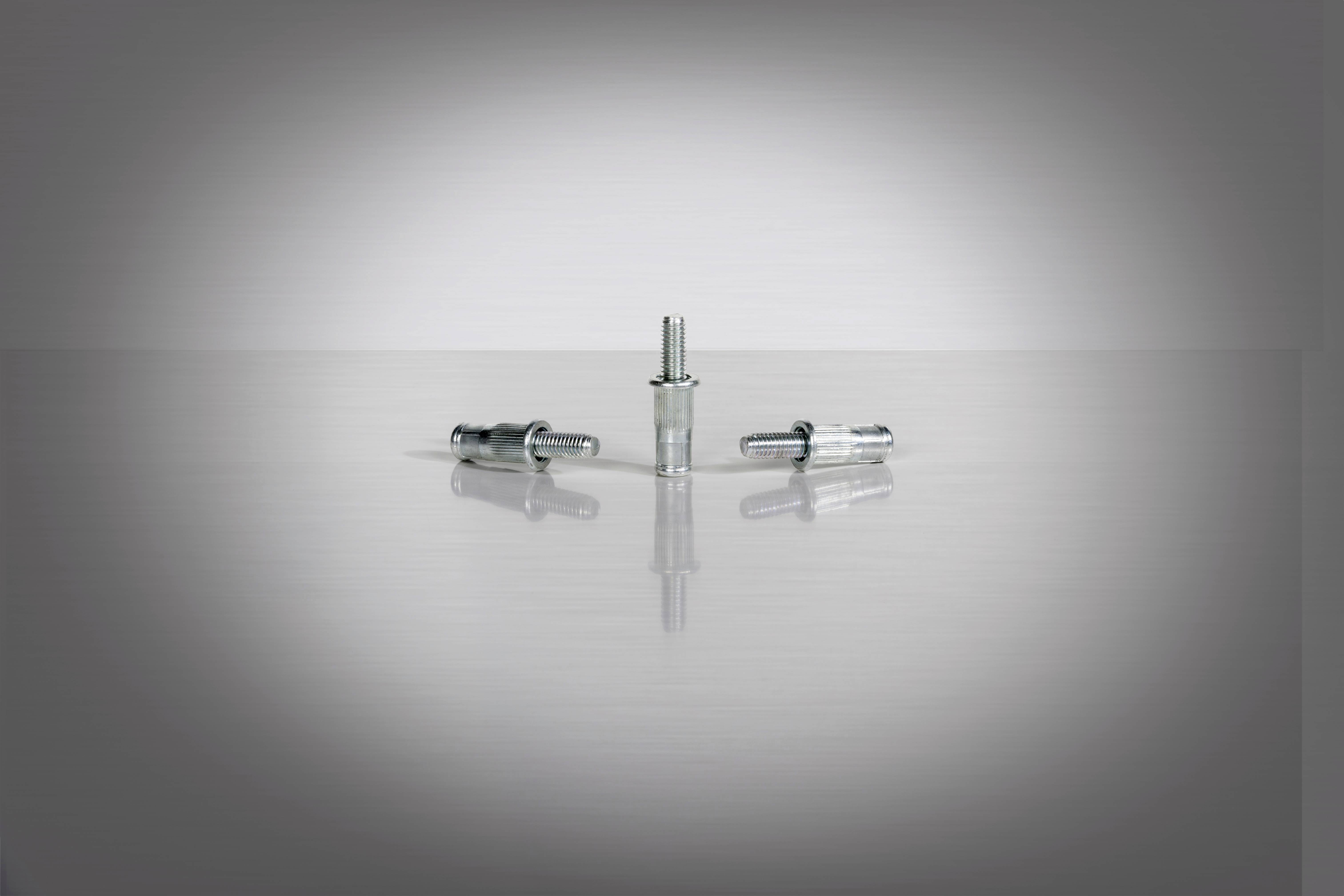 Trzy srebrne metalowe zamknięcia na błyszczącej powierzchni, jedno w pozycji pionowej, dwa w poziomej, tworzą symetryczne zestawienie.