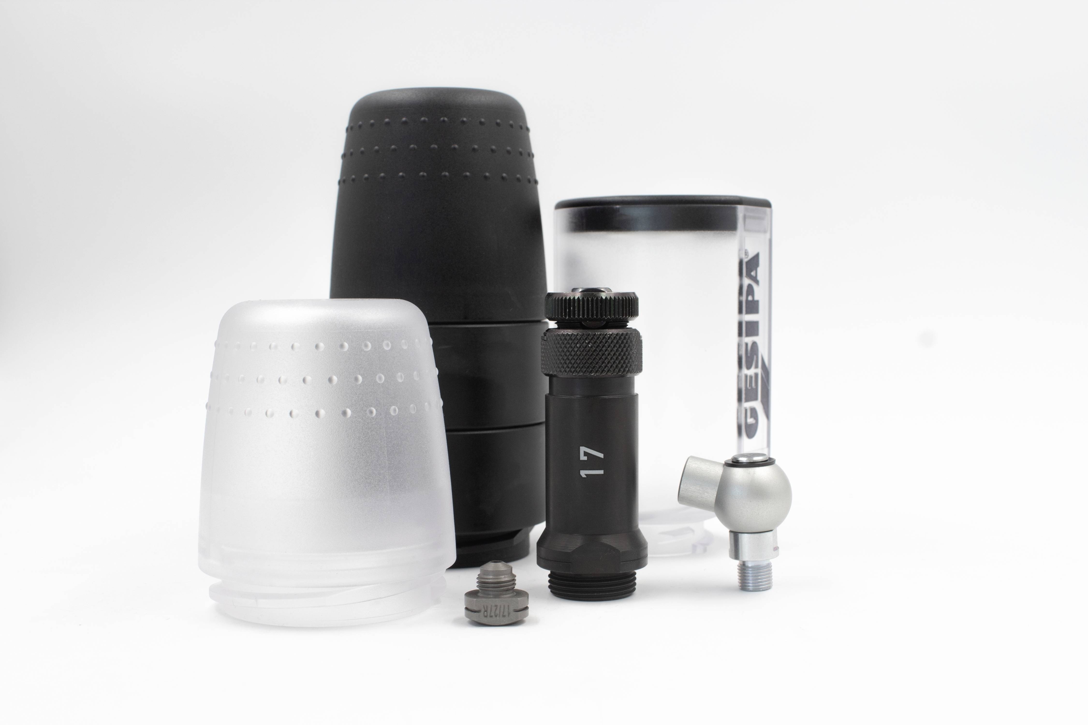 Różne nasadki i części akcesoriów na białym tle. Niektóre są czarne, inne przezroczyste. Jedna z nasadek ma numer '17'.