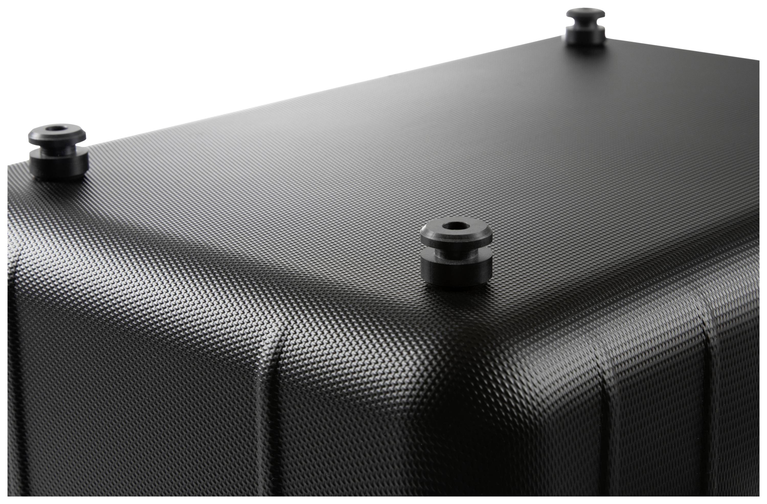 Czarna, prostokątna skrzynka o delikatnie strukturowanej powierzchni. Na górze znajdują się cztery okrągłe metalowe nóżki zapewniające stabilność.