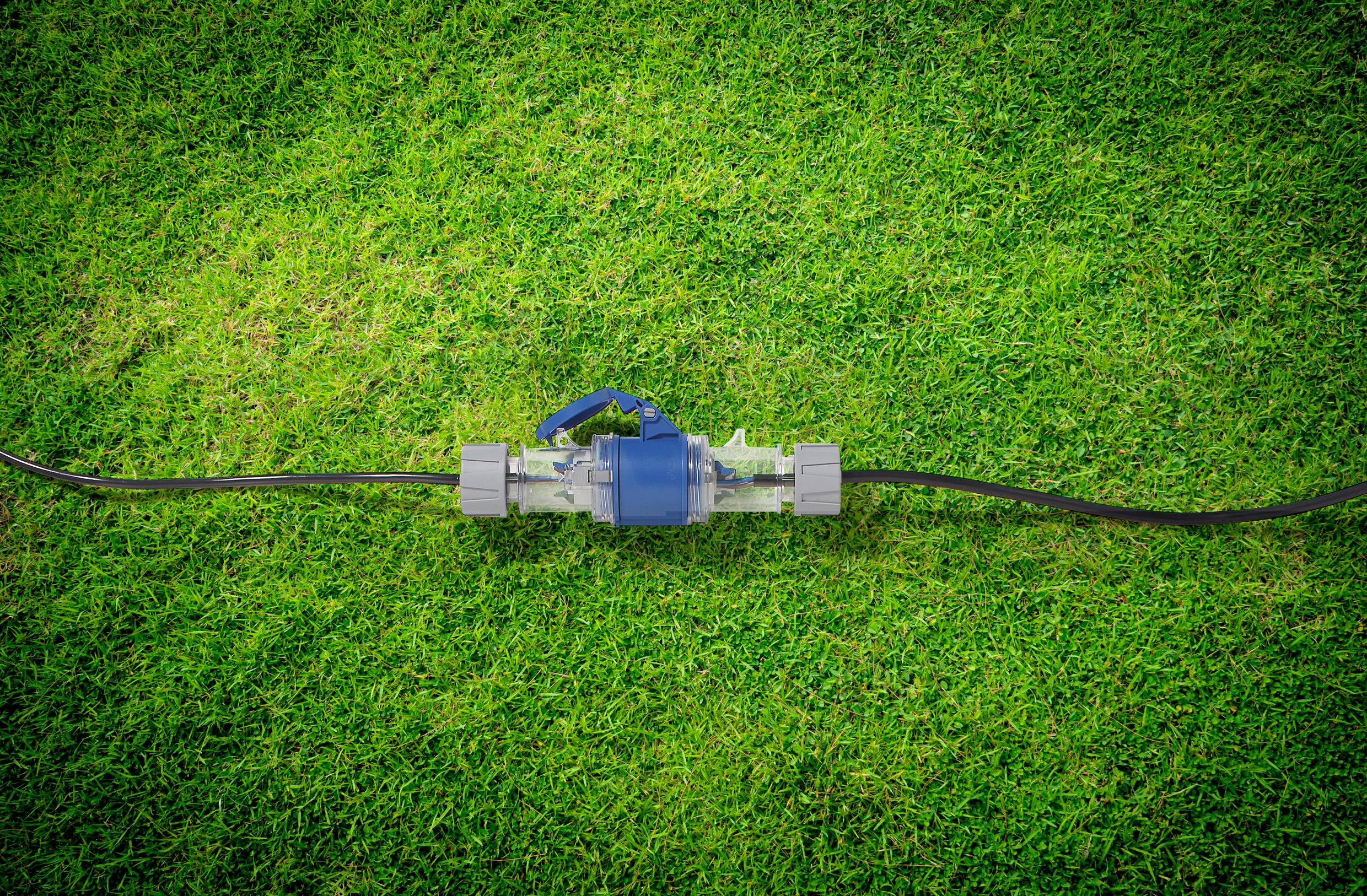 Niebieska pompa wodna leży na zielonej trawie z wężami po obu końcach.