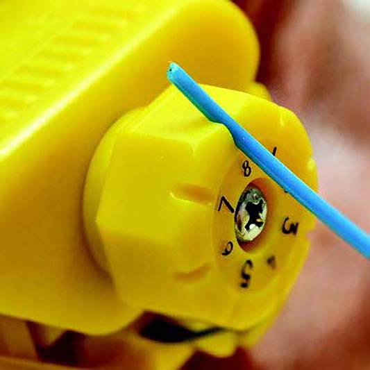 Żółty pokrętło na maszynie, oznaczone numerami od 0 do 5. Niebieski wskaźnik wskazuje na liczbę 4.