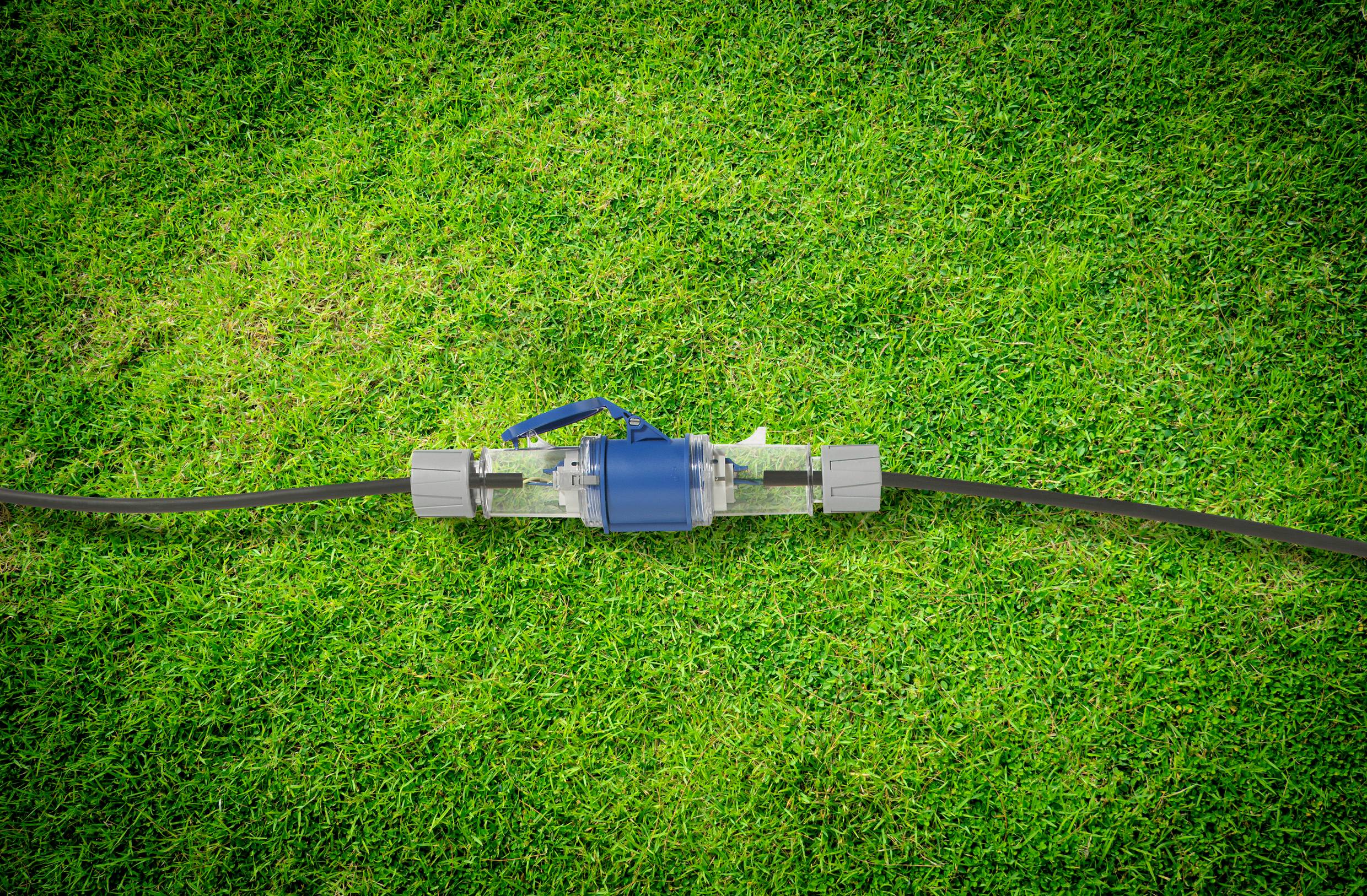 Przezroczysta pompa wodna z niebieską obudową jest zintegrowana z wężem ogrodowym na zielonej trawie.