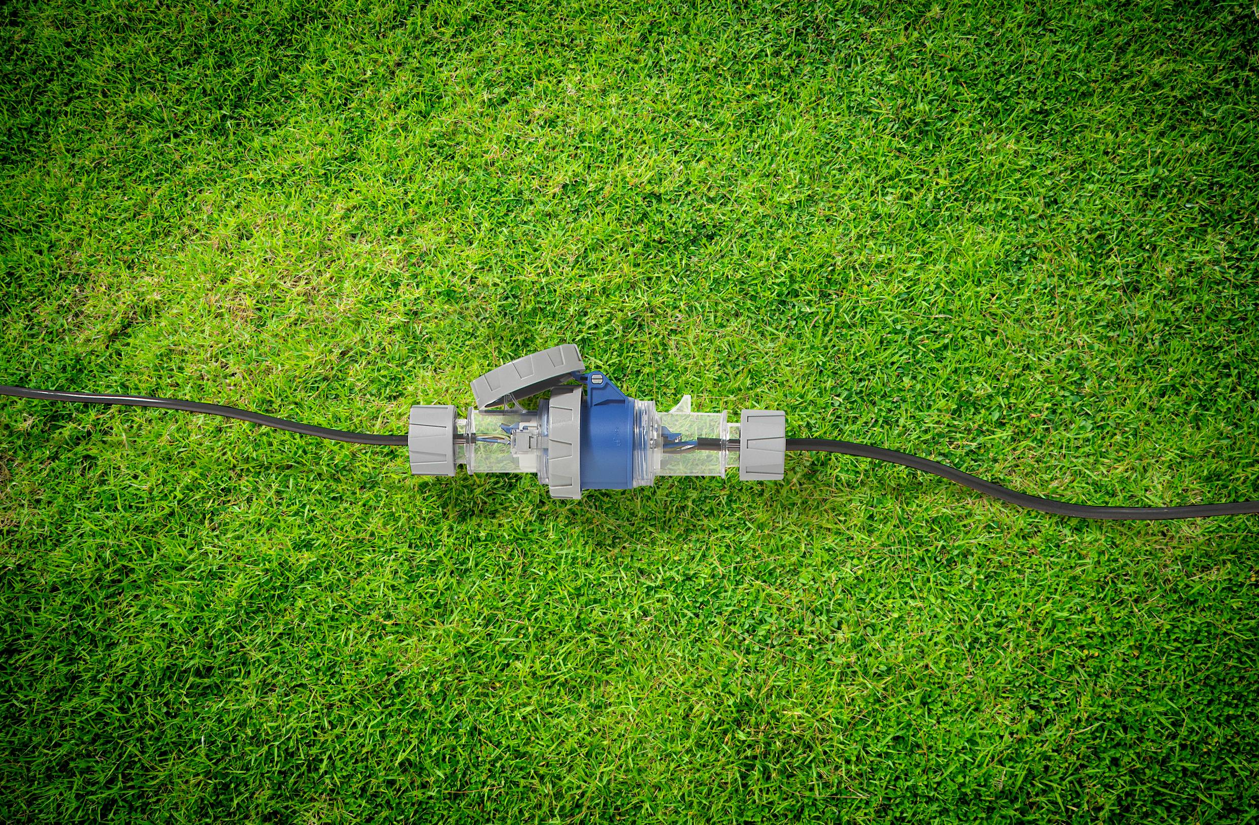 Pompa wodna z wężem leży na zielonym trawniku.