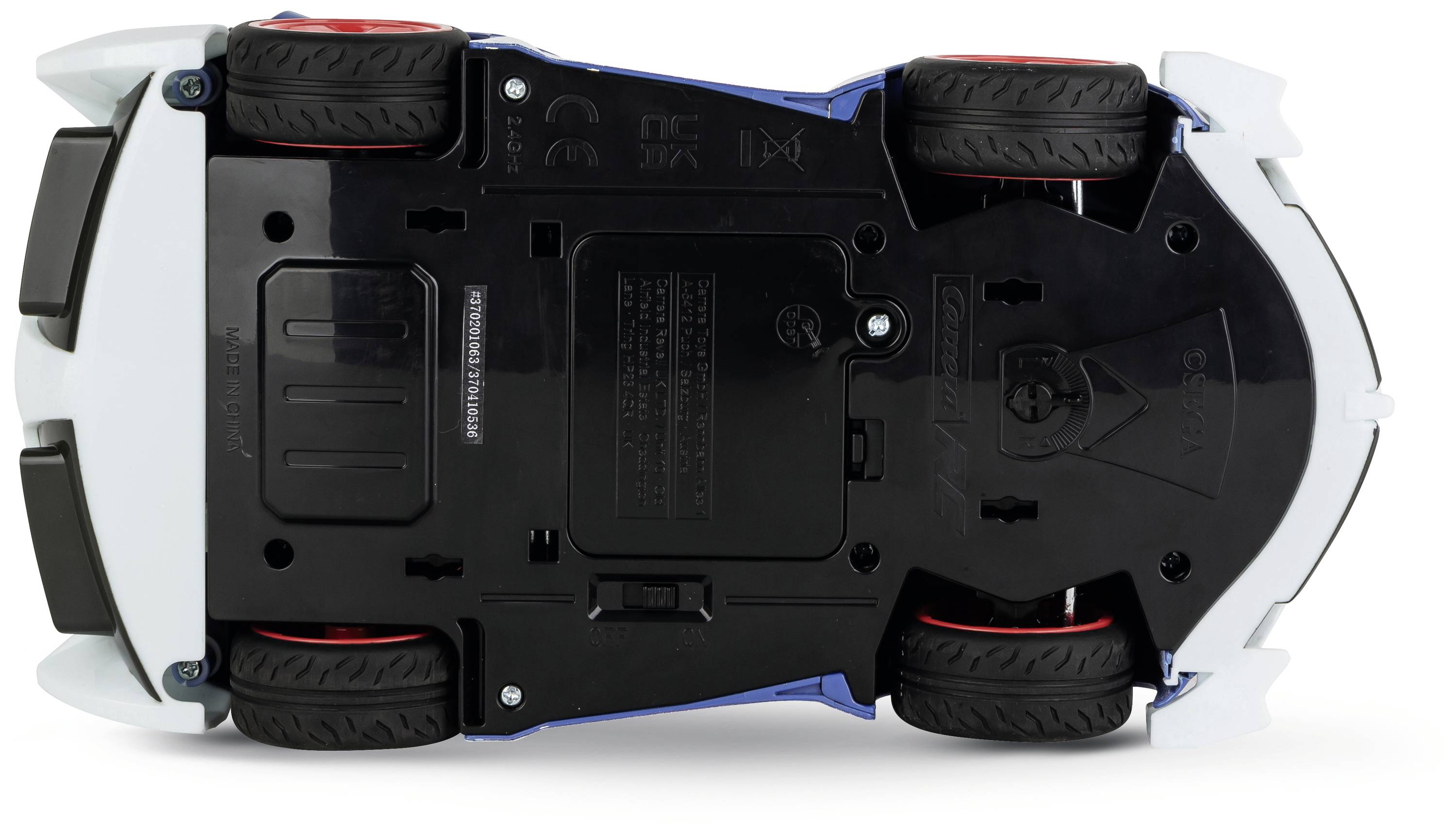 Zabawkowy samochodzik widziany od spodu: widok na koła, komorę baterii i informacje producenta. Opony wykazują ślady użytkowania.