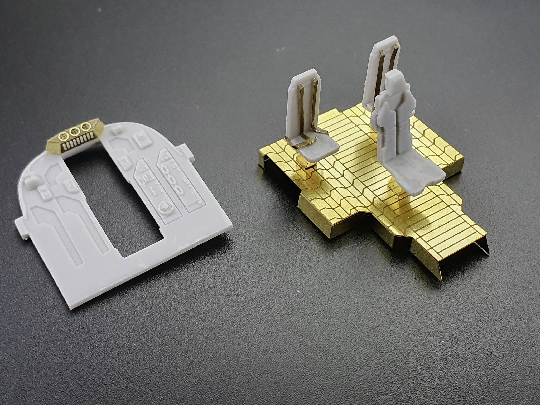 Białe i złote elementy modelu na czarnym tle, prawdopodobnie części modelu architektonicznego lub technicznego.