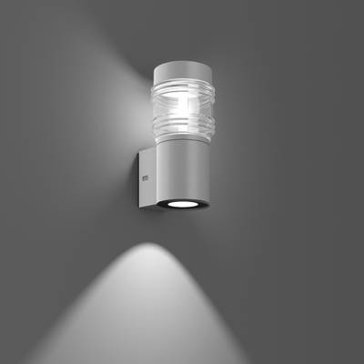 Lampa zewnętrzna wykonana z metalu i szkła na szarej ścianie, emitująca światło w górę i w dół.