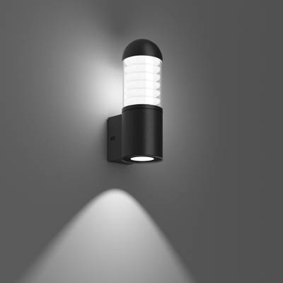 Czarna lampa ścienna na szarej ścianie, świecąca w górę i w dół. Nowoczesna, cylindryczna forma z prążkowanym dyfuzorem szklanym.