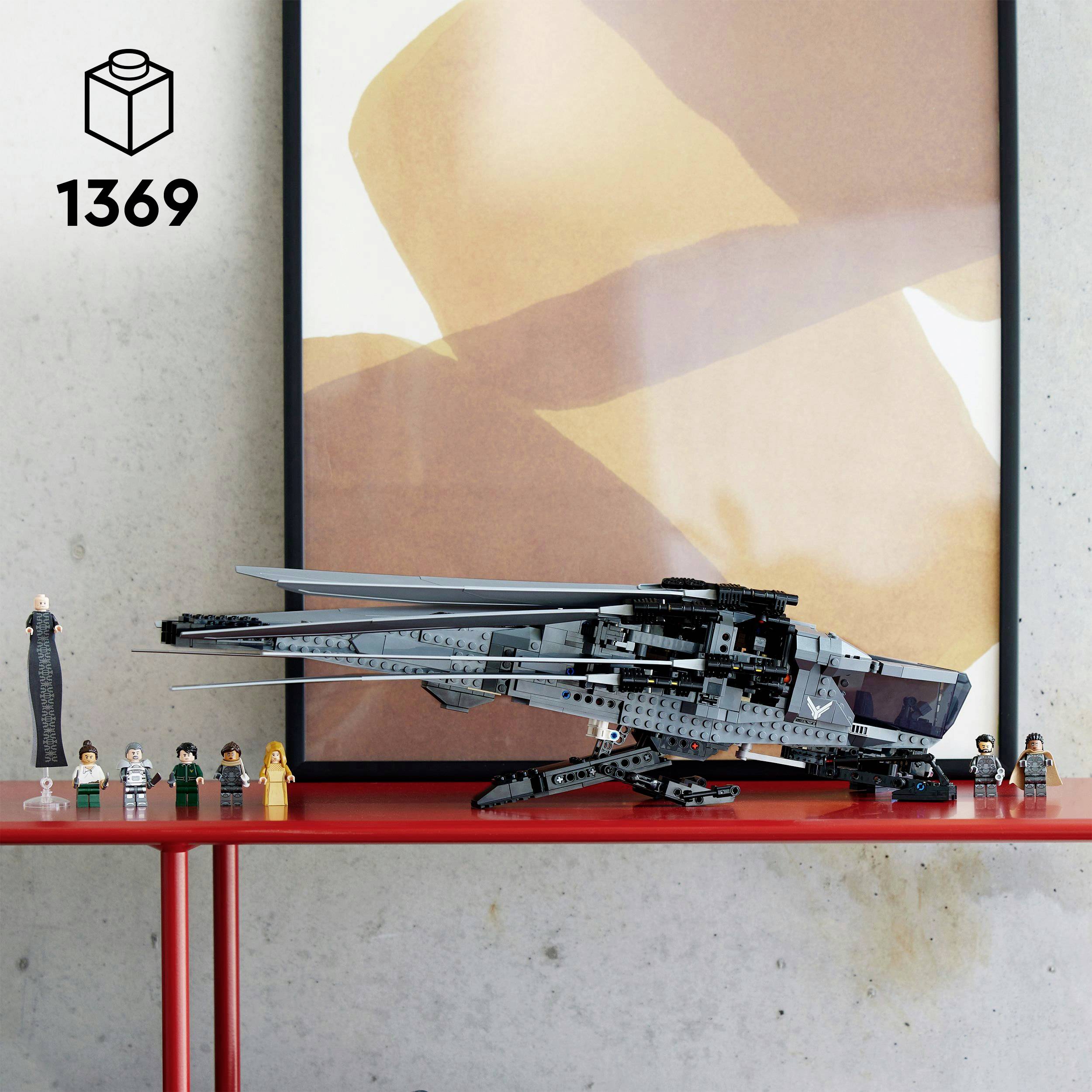 'Zestaw Lego 1369, szczegółowy widok statku kosmicznego science fiction na czerwonym stole. Tło: abstrakcyjny obraz na szarej ścianie.'