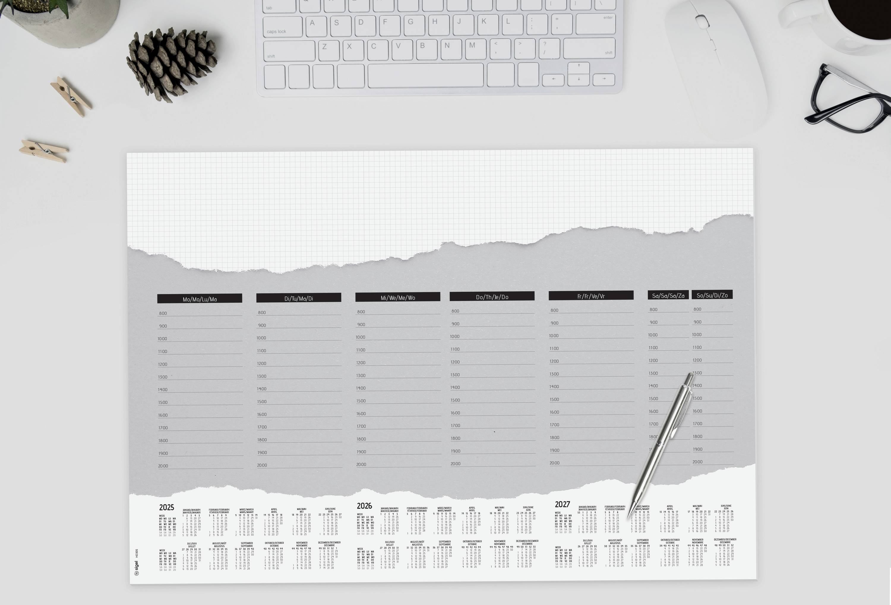 Widok z biurka z kalendarzem, notatnikiem, długopisem, klawiaturą, myszką i filiżanką kawy. Notes pokazuje widok tygodnia w miesiącu.