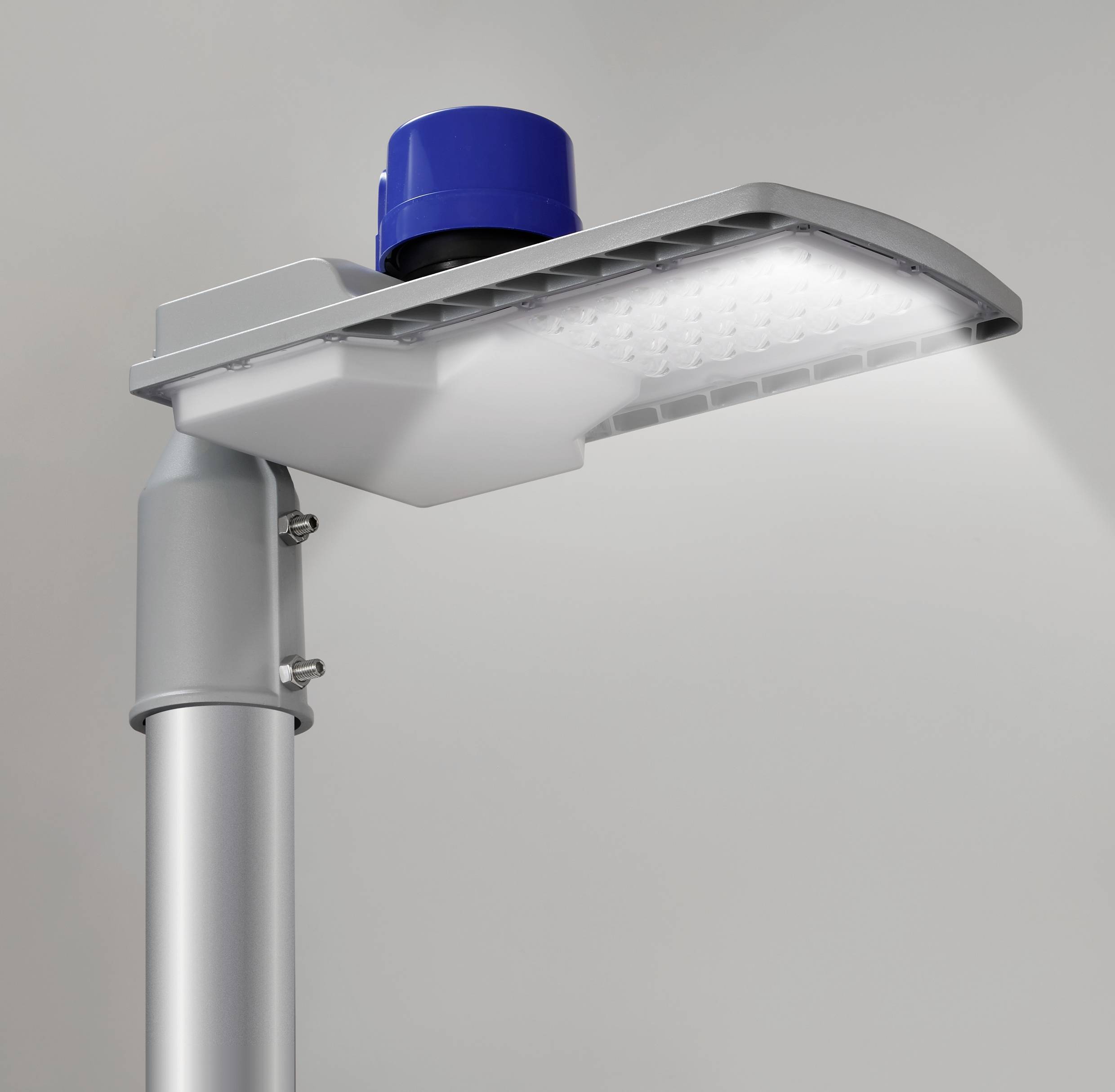 Nowoczesna lampa uliczna LED z niebieskim czujnikiem na górze, świecąca jasno na szarym tle.