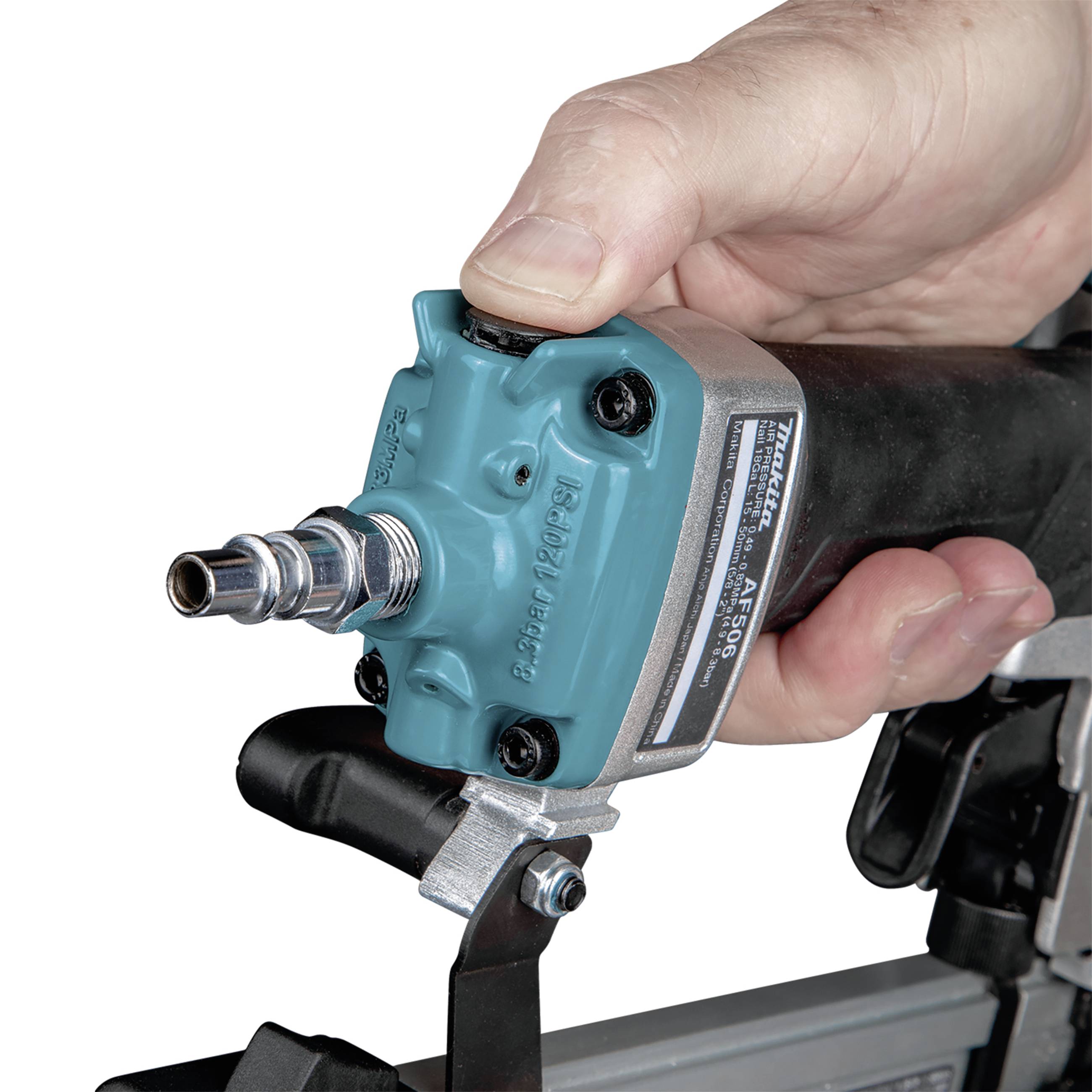 Jedna ręka trzyma gwoździarkę pneumatyczną, gotową do użycia. Widoczny jest przedni koniec i spust.