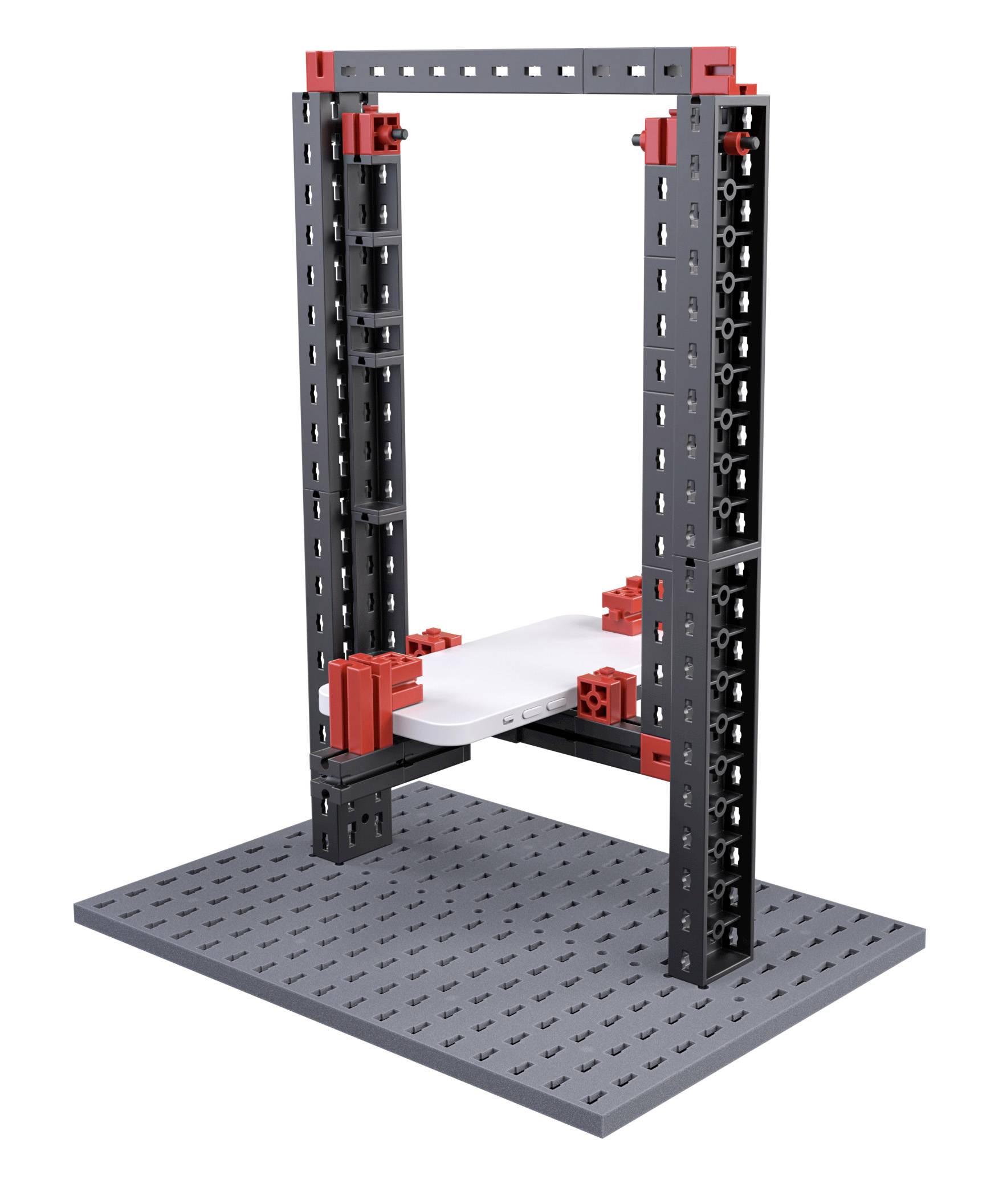Model konstrukcyjny LEGO przedstawia prostokątną ramę wykonaną z czerwonych i czarnych elementów, umieszczoną na szarej podstawie.
