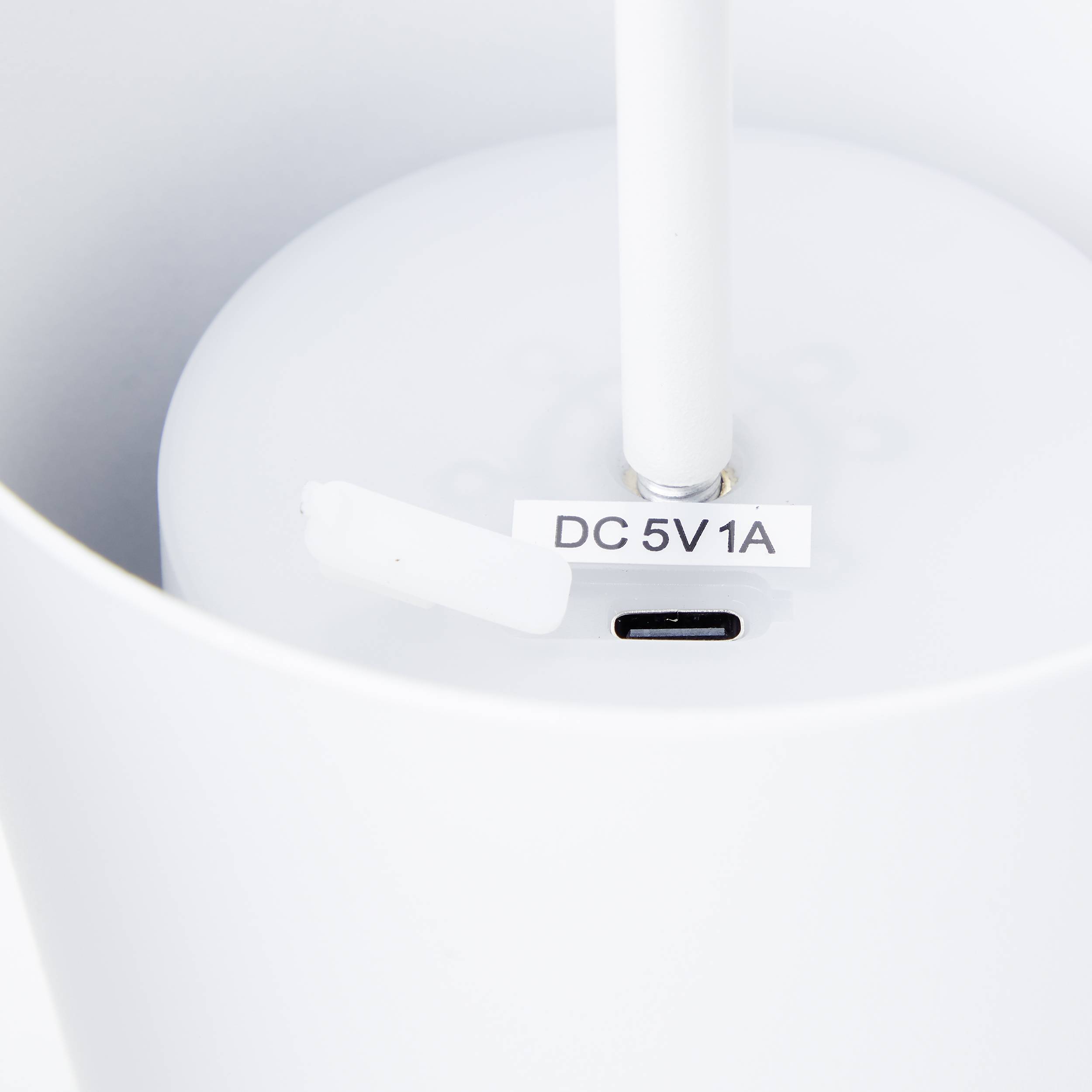 Zbliżenie białego urządzenia elektronicznego z gniazdem USB-C, oznaczonego napisem 'DC 5V 1A', na białym tle.