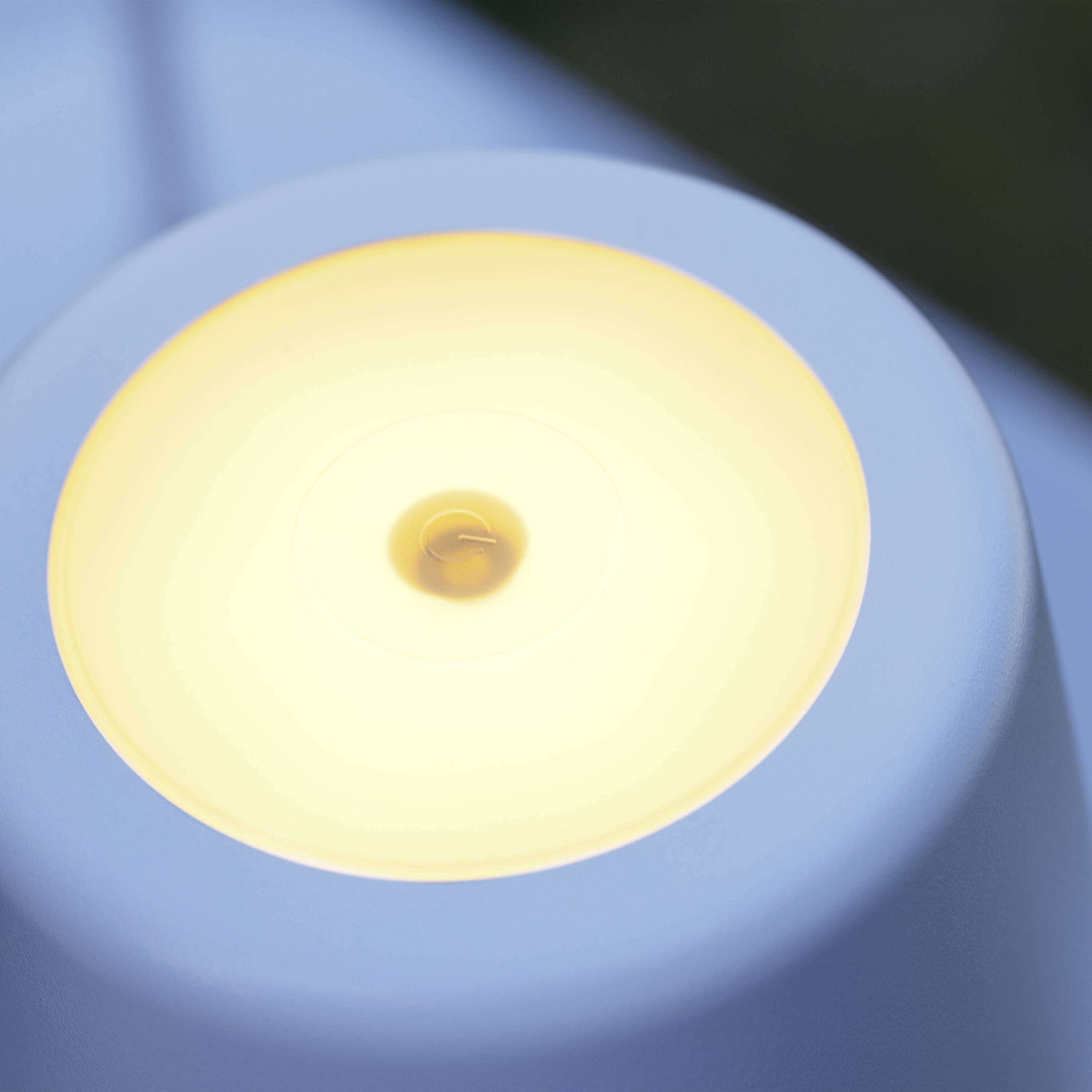 Zbliżenie okrągłej, żółto świecącej lampy w nowoczesnym stylu, na rozmytym tle.