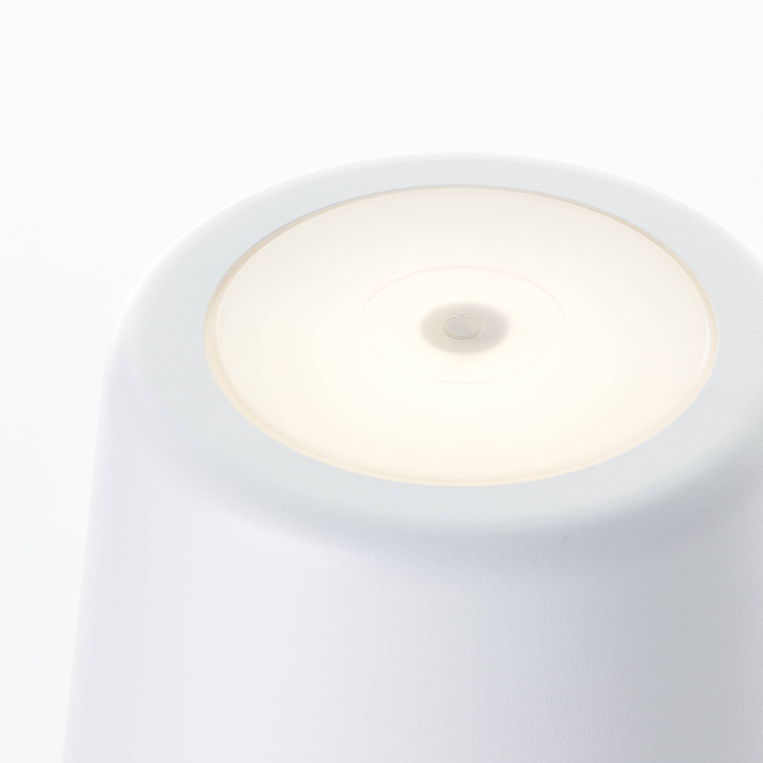 Biała, stożkowa lampa z miękkim światłem na górnej powierzchni; nowoczesny, minimalistyczny design.