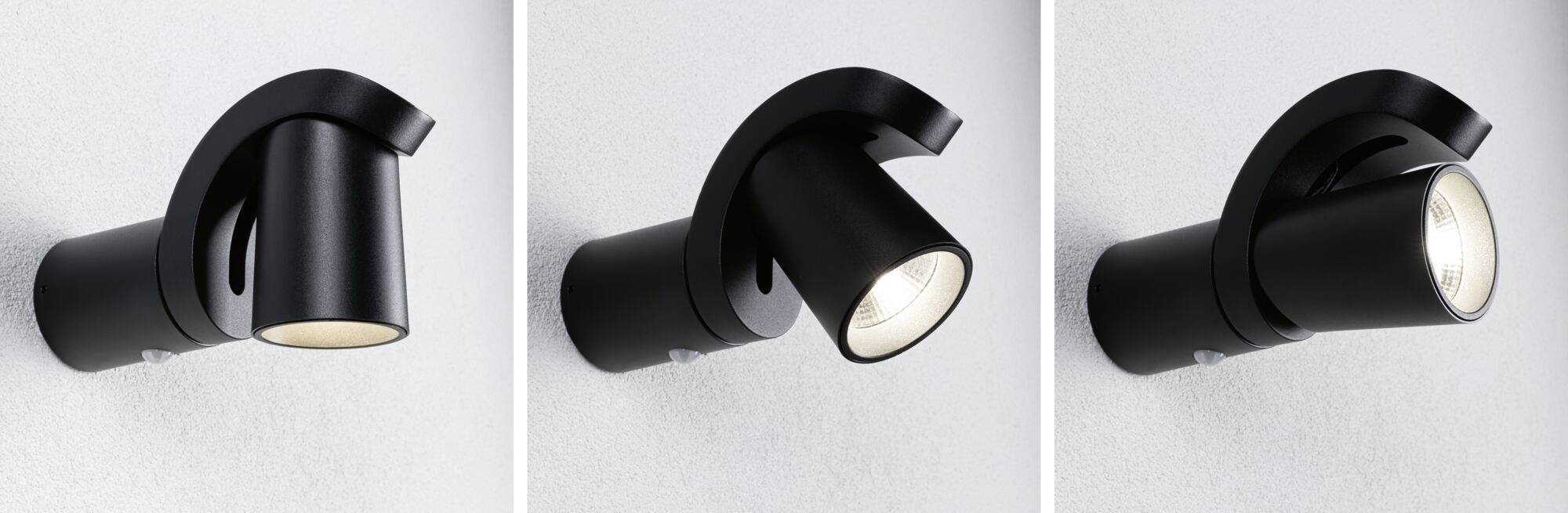Trzy czarne kinkiety na szarej ścianie, ustawione pod różnymi kątami nachylenia, każdy o innej intensywności świecenia.