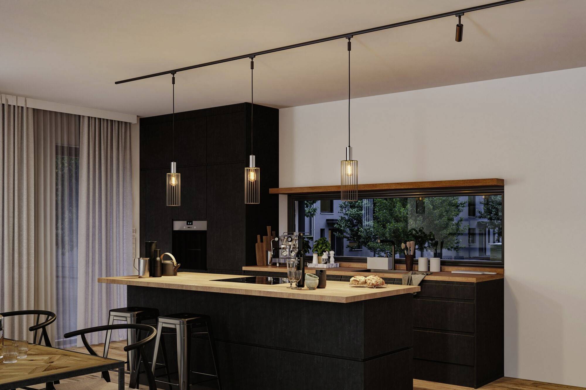 Otwarta, nowoczesna kuchnia z ciemnymi szafkami, drewnianym blatem, trzema wiszącymi lampami nad blatem roboczym oraz oknem z widokiem na zieleń.