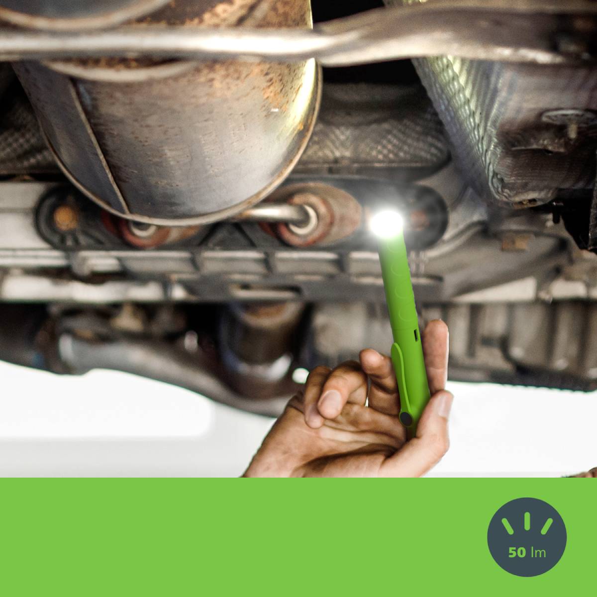 Mechanik sprawdza podwozie samochodu małą latarką kieszonkową.