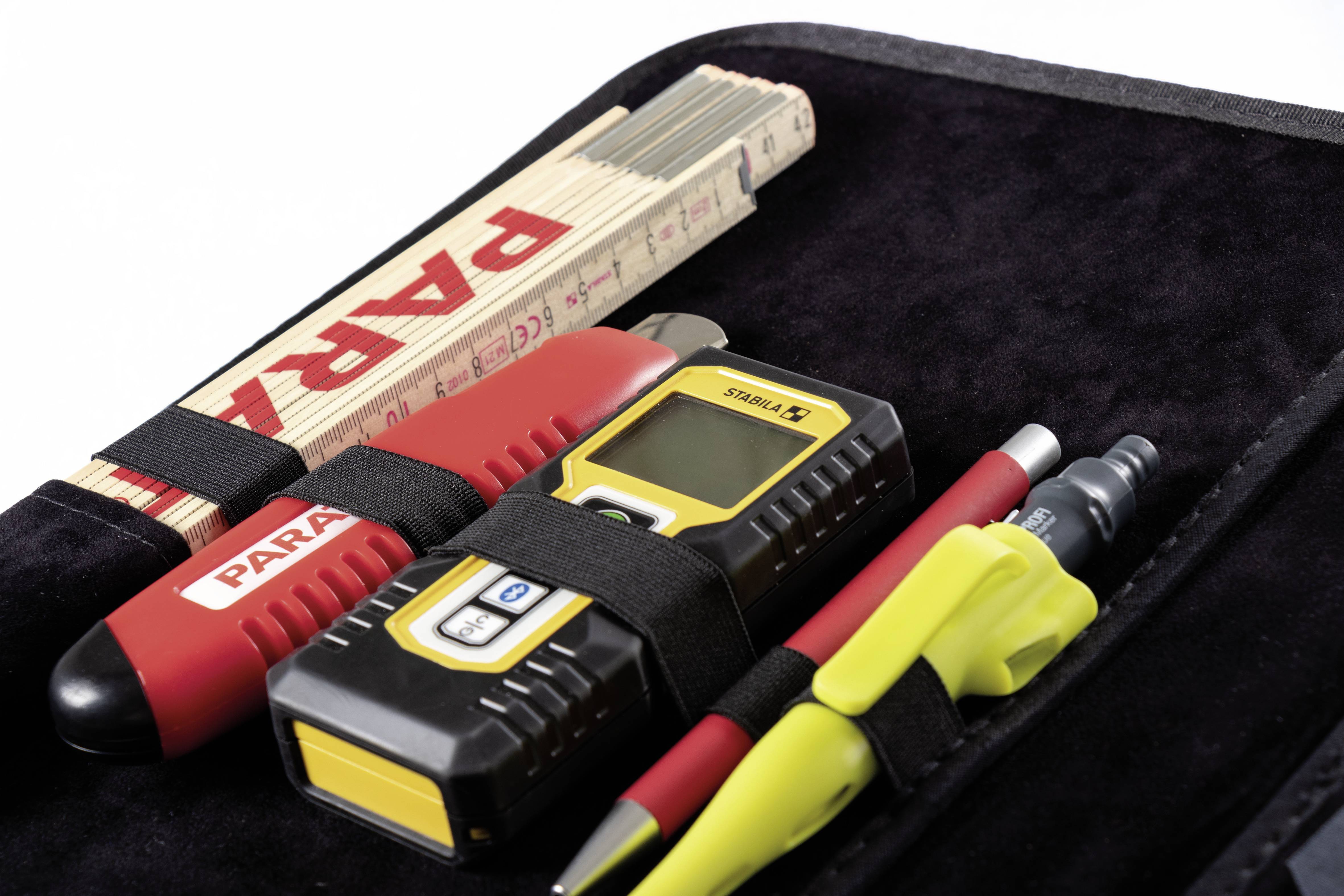 Zestaw narzędzi z miarką składaną, cyfrowym urządzeniem pomiarowym, czerwonym i żółtym długopisem w czarnej torbie.