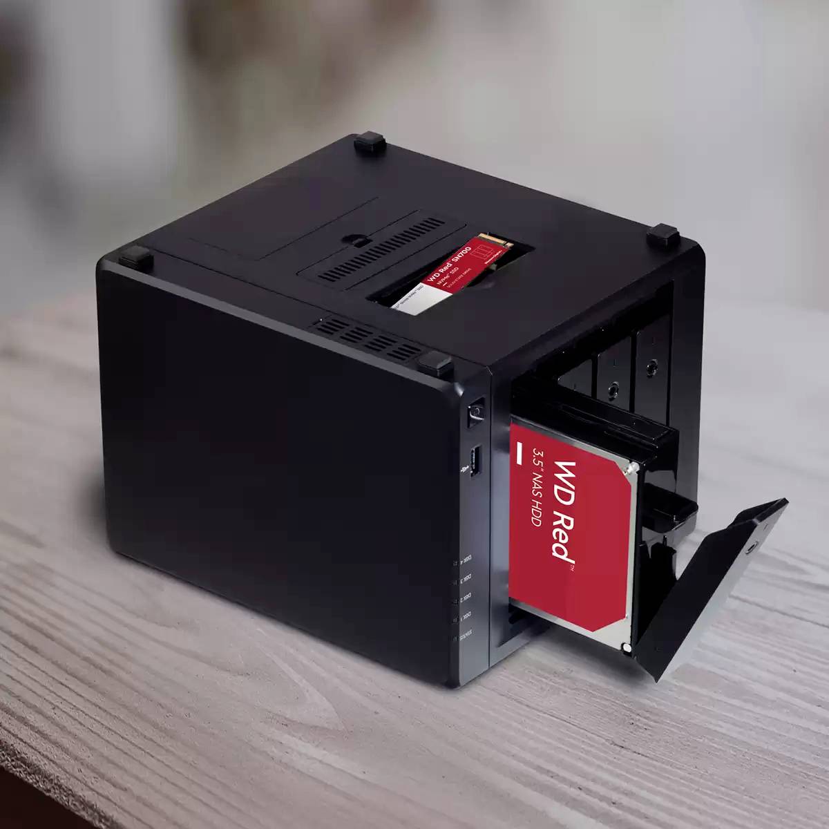 Czarny, zewnętrzny serwer plików NAS z wysuniętą kieszenią, w której widoczny jest czerwony dysk twardy WD Red 3.5 NAS HDD.